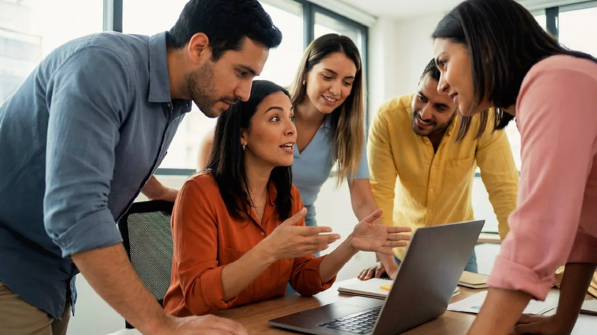 Marketing team discussing insights and strategy around a laptop during a collaborative working session.