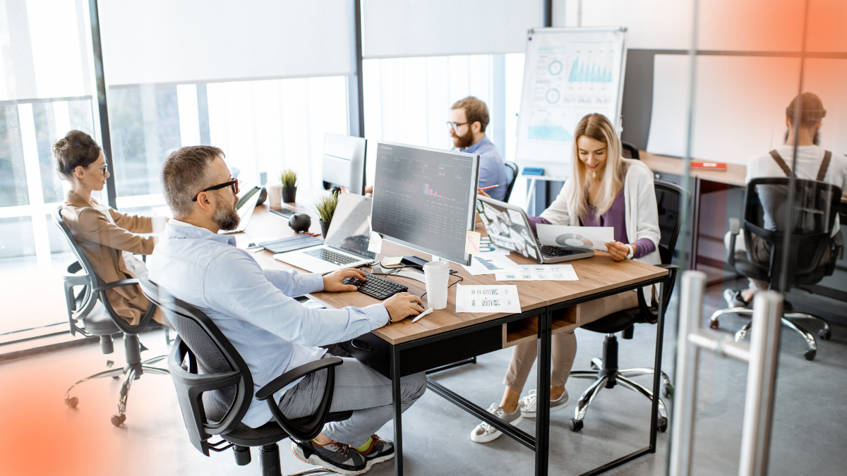 Team working in a modern office with analytics displayed across computer screens and reports, representing AI-powered data analysis and strategic business decision-making.