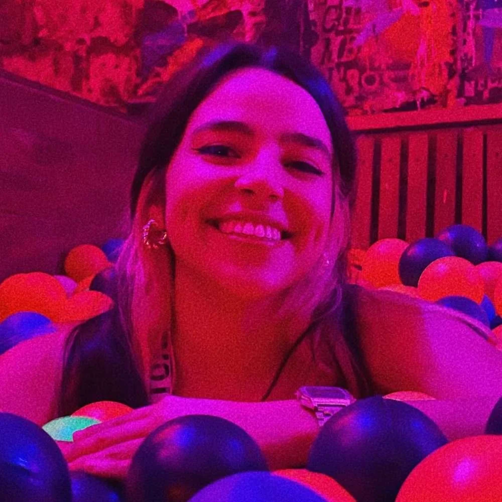 A woman smiling in a colorful ball pit with neon lighting