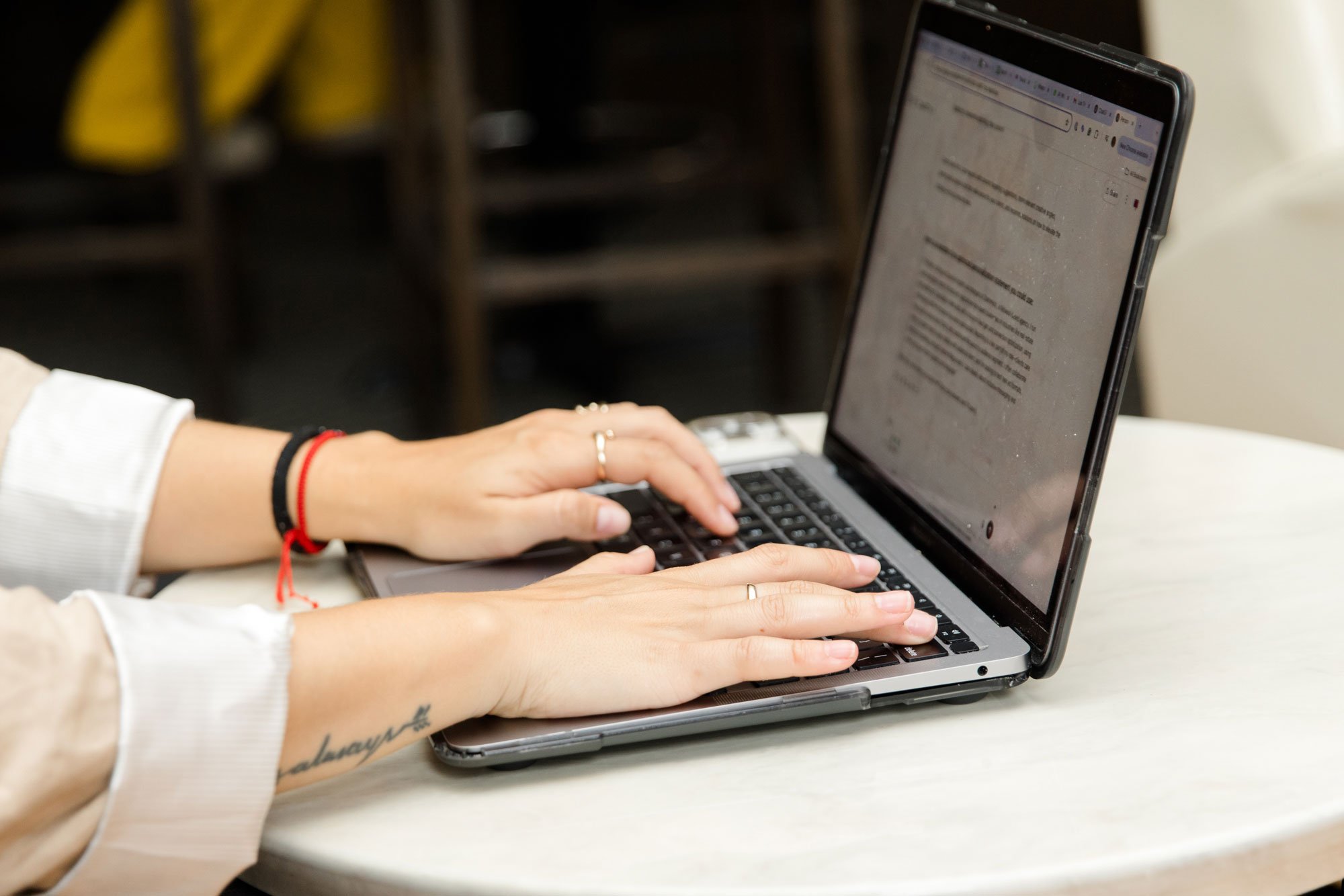 Person using a laptop on a white table, with hands typing on the keyboard.