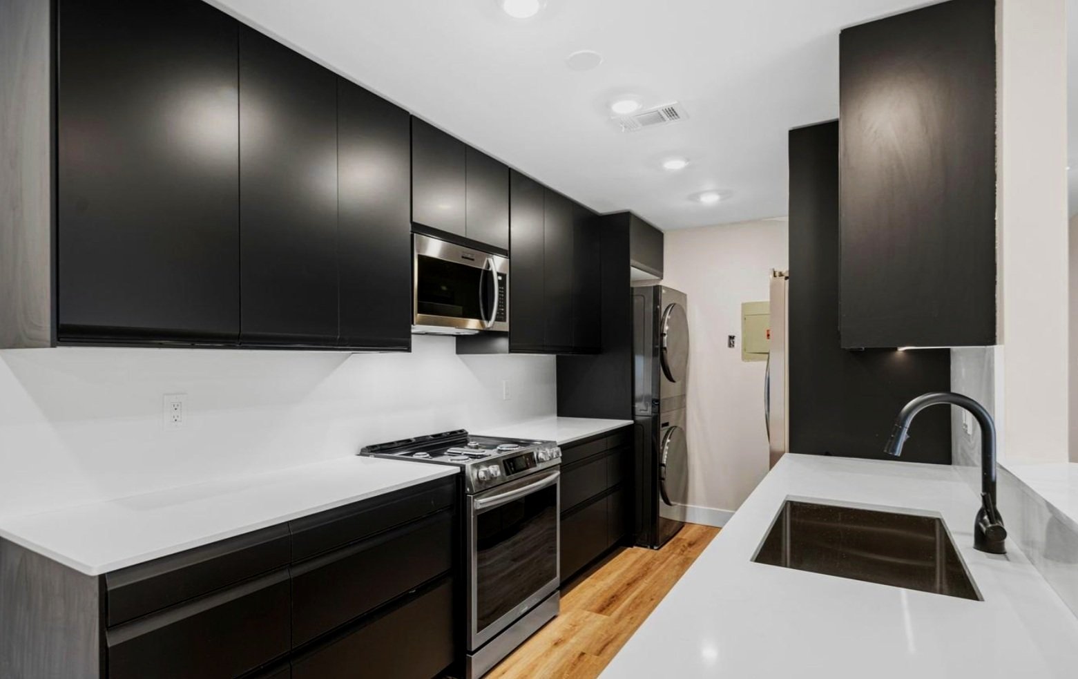 Modern kitchen with black cabinets, stainless steel appliances, and a white countertop
