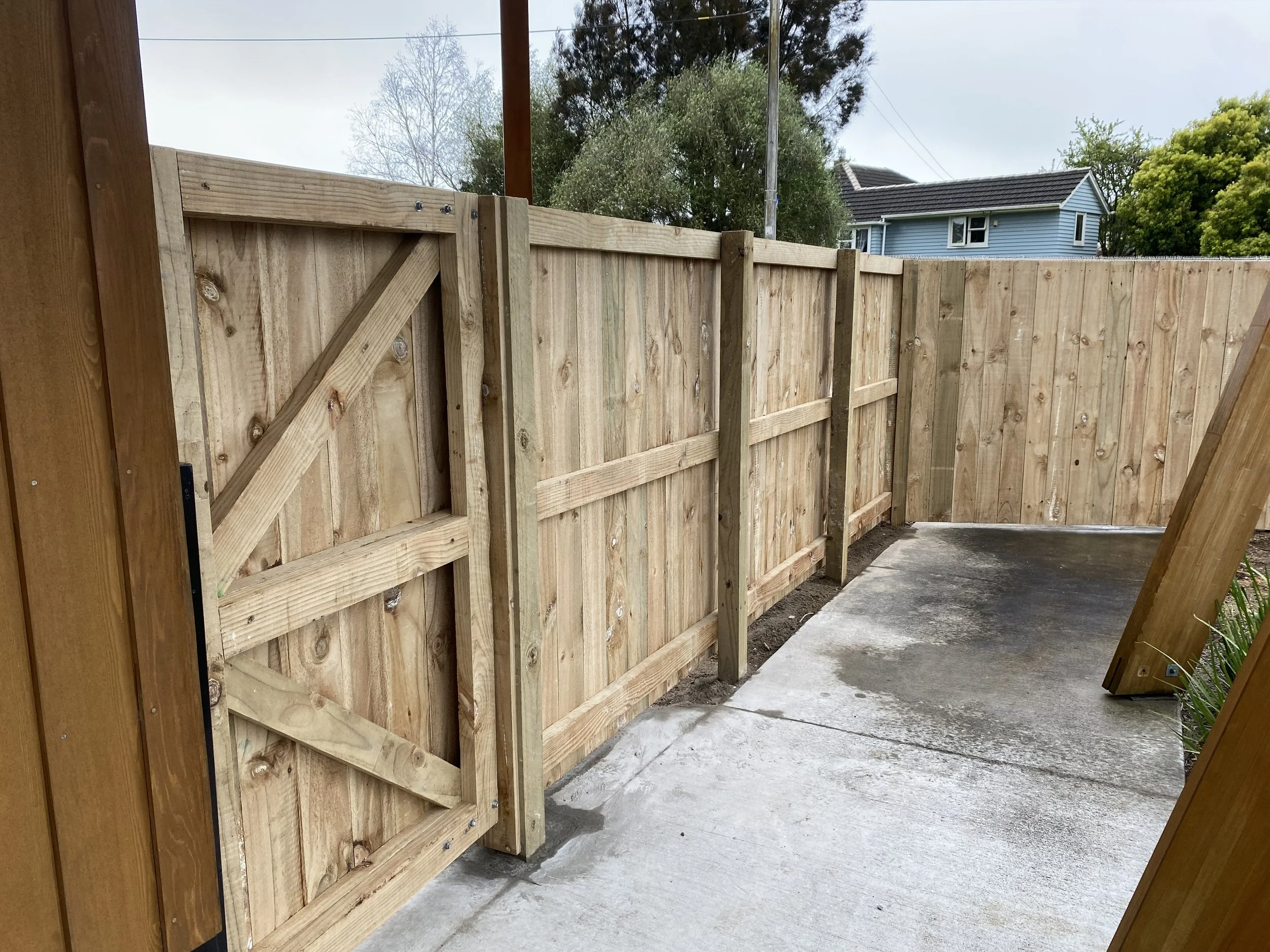 Wooden privacy fence with gate on a concrete path renovated