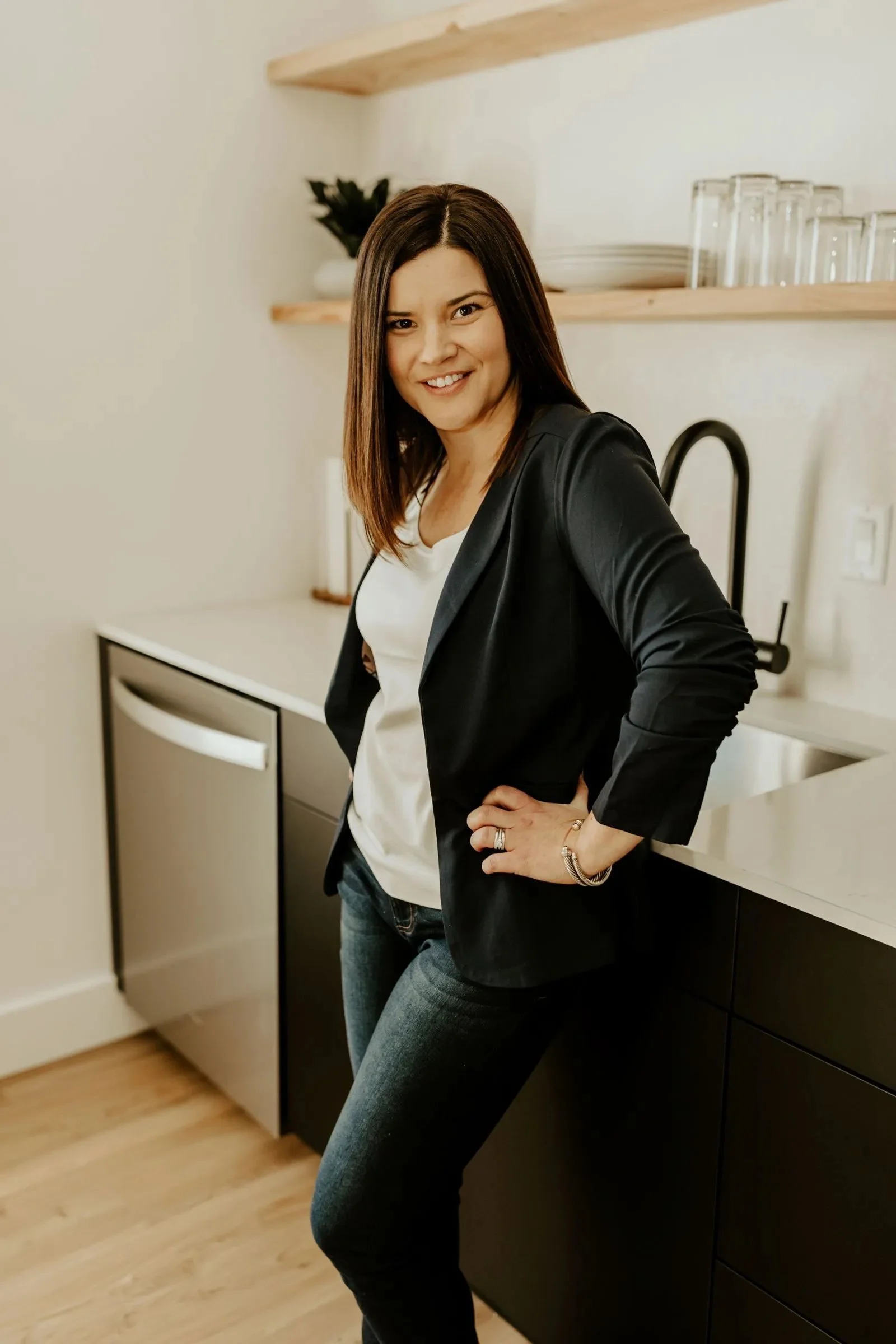 Jen Schimbeno smiling and leaning against the counter, ready to talk about conscious co-parenting, child-focused parenting plans, and values and interest-based financial agreements.
