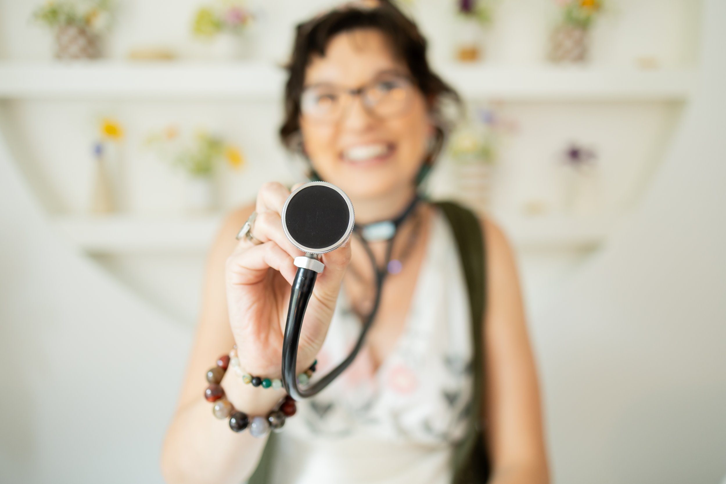 Close-up of stethoscope held by Dr. Bobi Farrow, with Dr. Farrow blurred in the background at an offsite location