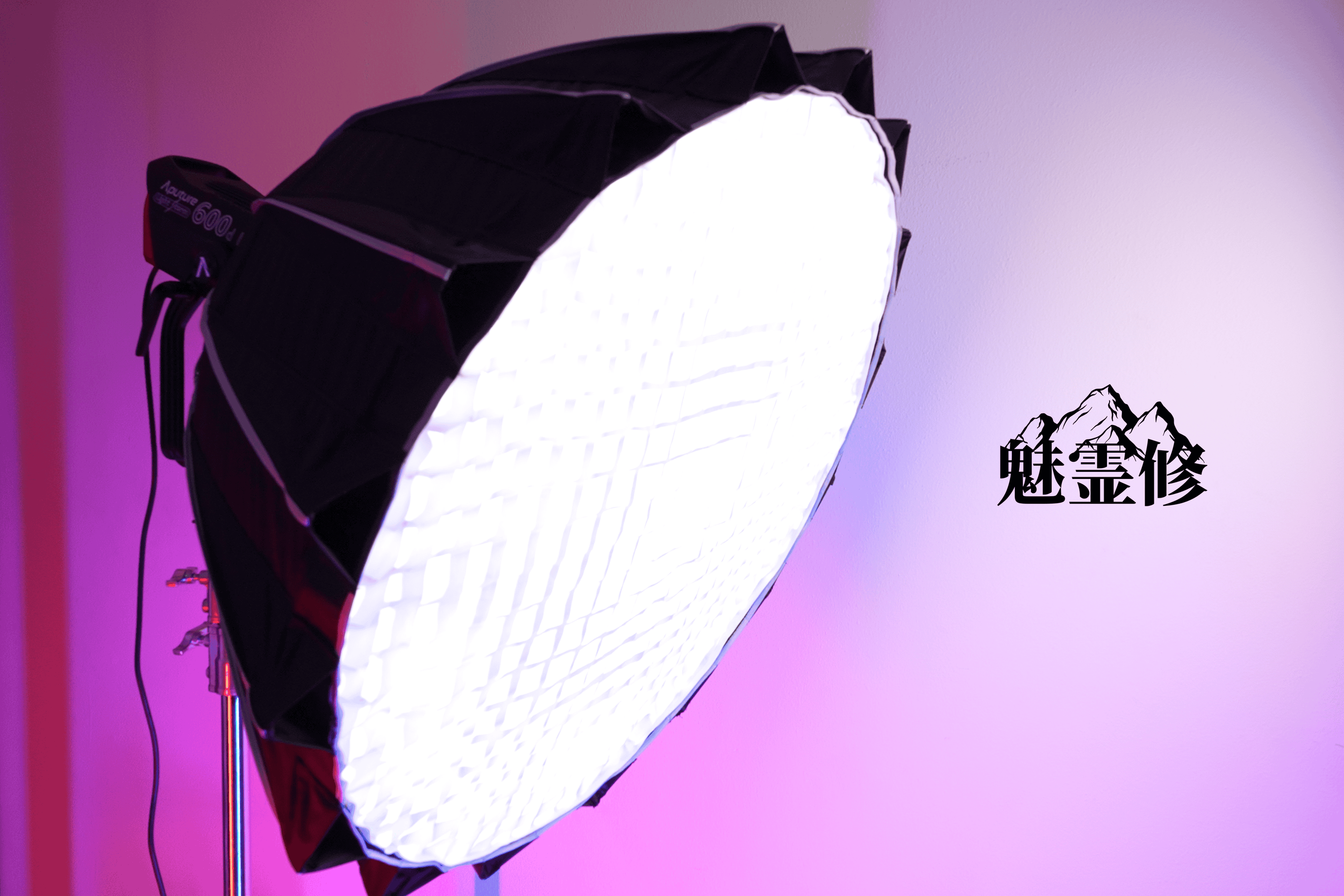 A photo of a large, illuminated rectangular softbox light with a black outer frame, set against a pink and purple gradient background. There are some black Chinese characters in the bottom right corner of the image.