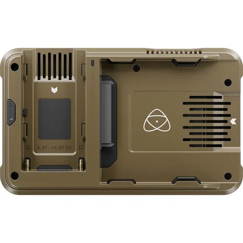 The image shows the bottom of a tan or khaki-colored electronic device, possibly a drone or camera, with various slots, vents, a battery compartment, and some symbols.