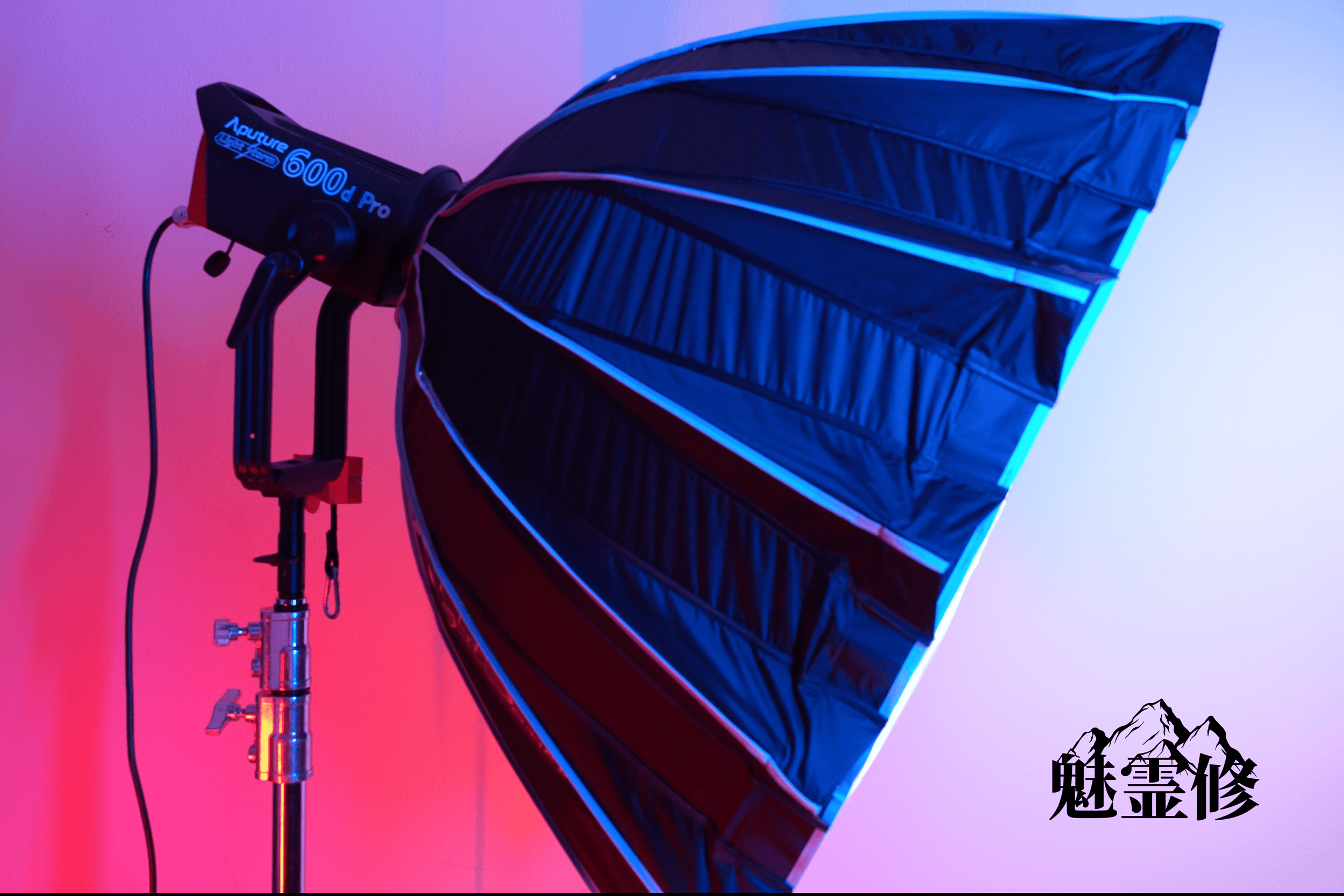 A black photography softbox with blue and purple lighting effects, mounted on a stand against a gradient pink and purple background, with Chinese characters in black at the bottom right.