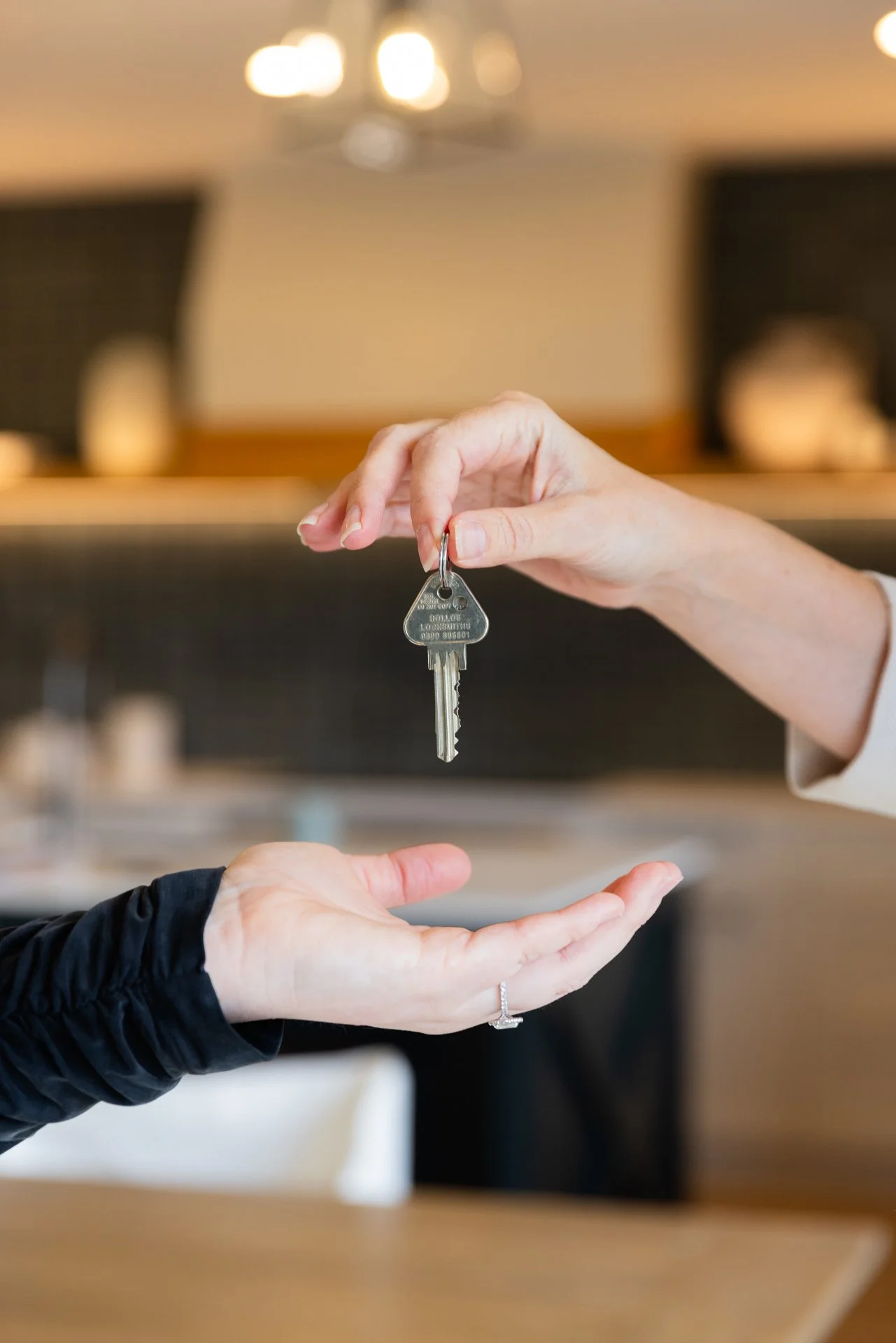 Person handing over a car key to another person inside a room.