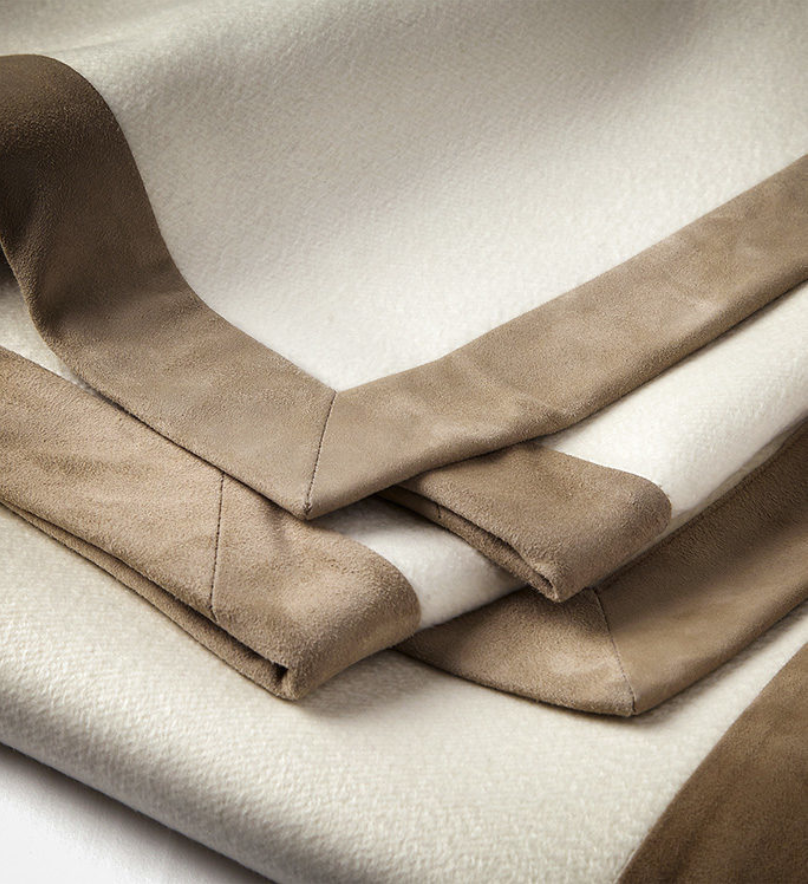 Stack of beige and white fabric or upholstery materials, some with a suede-like texture.