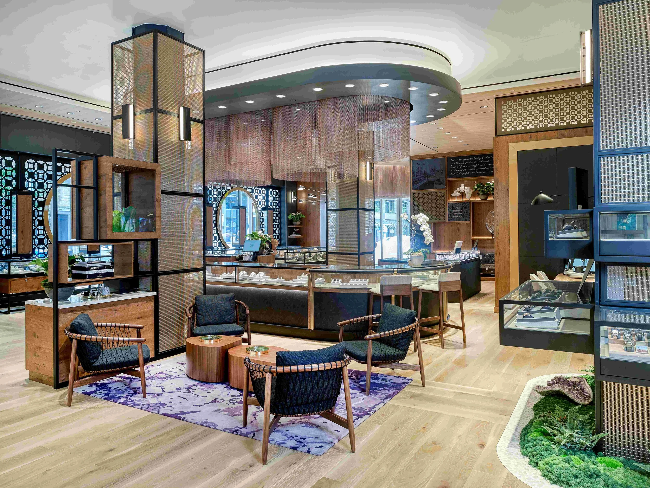 Interior of a modern jewelry store with display cases, seating area, and decorative elements.
