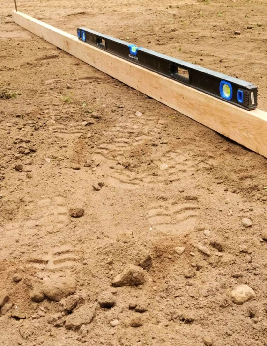 Picture of dirt with a level attached to a piece of wood on it