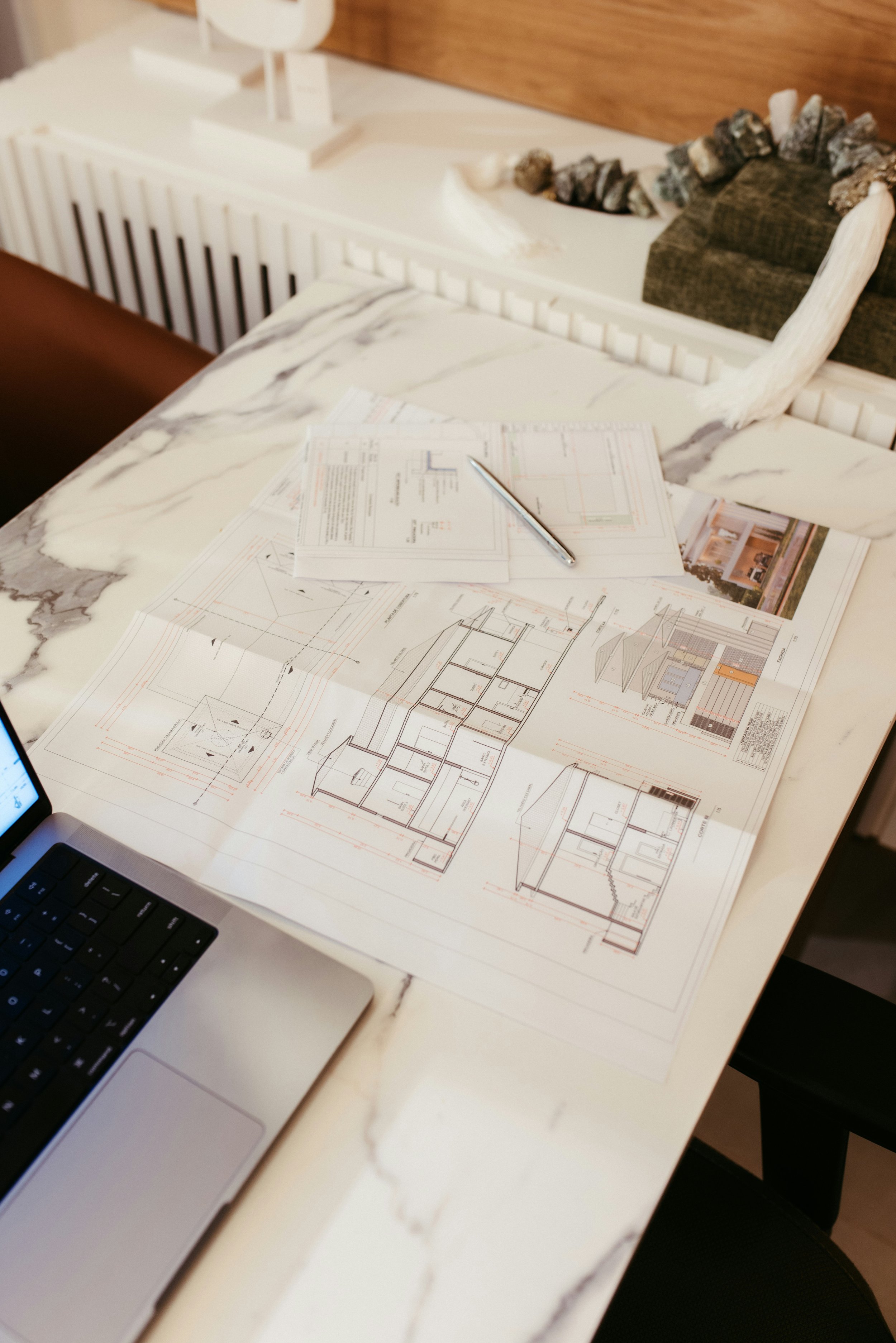 Blueprints or architectural plans on a clipboard on a wooden table with a cup in the background.