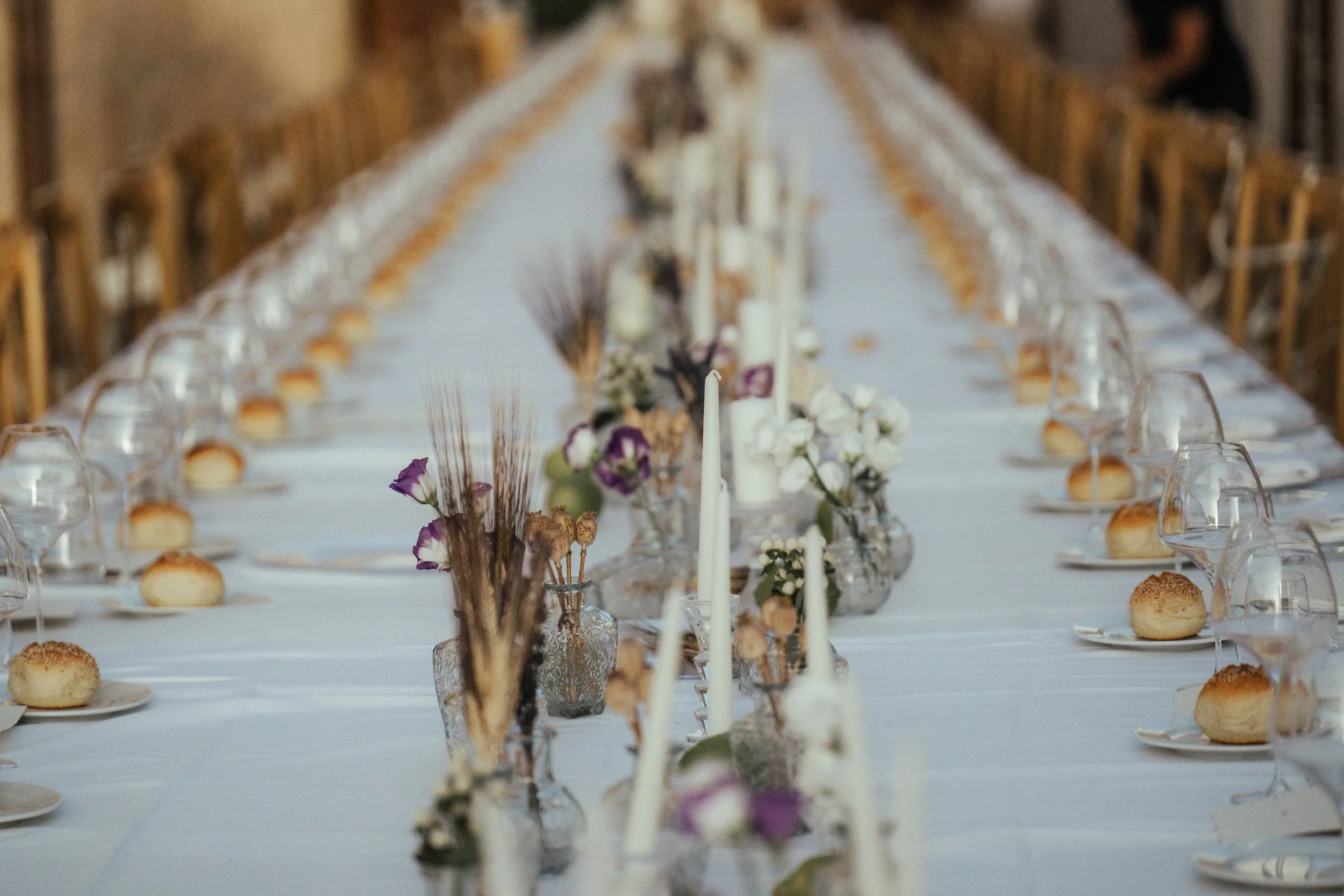 Long wedding reception table in Sicily with dried flowers, candles, white linen, and elegant rustic styling by Alla Flora Giapponese.
