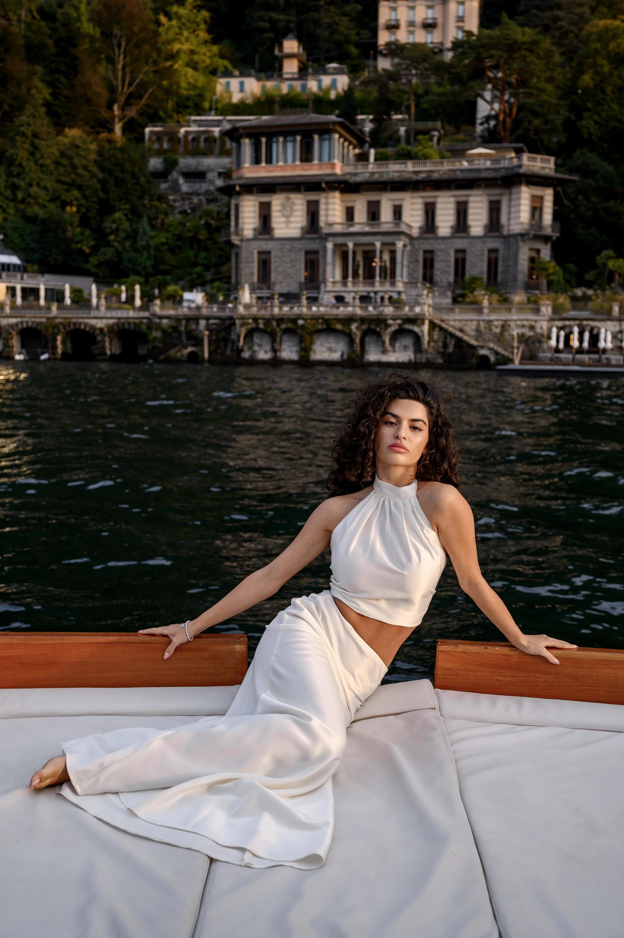 Editorial bridal portrait on Lake Como featuring a bride aboard a wooden boat surrounded by iconic lakeside villas.