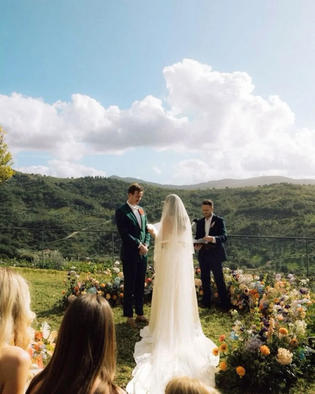 Outdoor symbolic wedding ceremony in Italy with bride and groom exchanging vows overlooking mountains and floral aisle