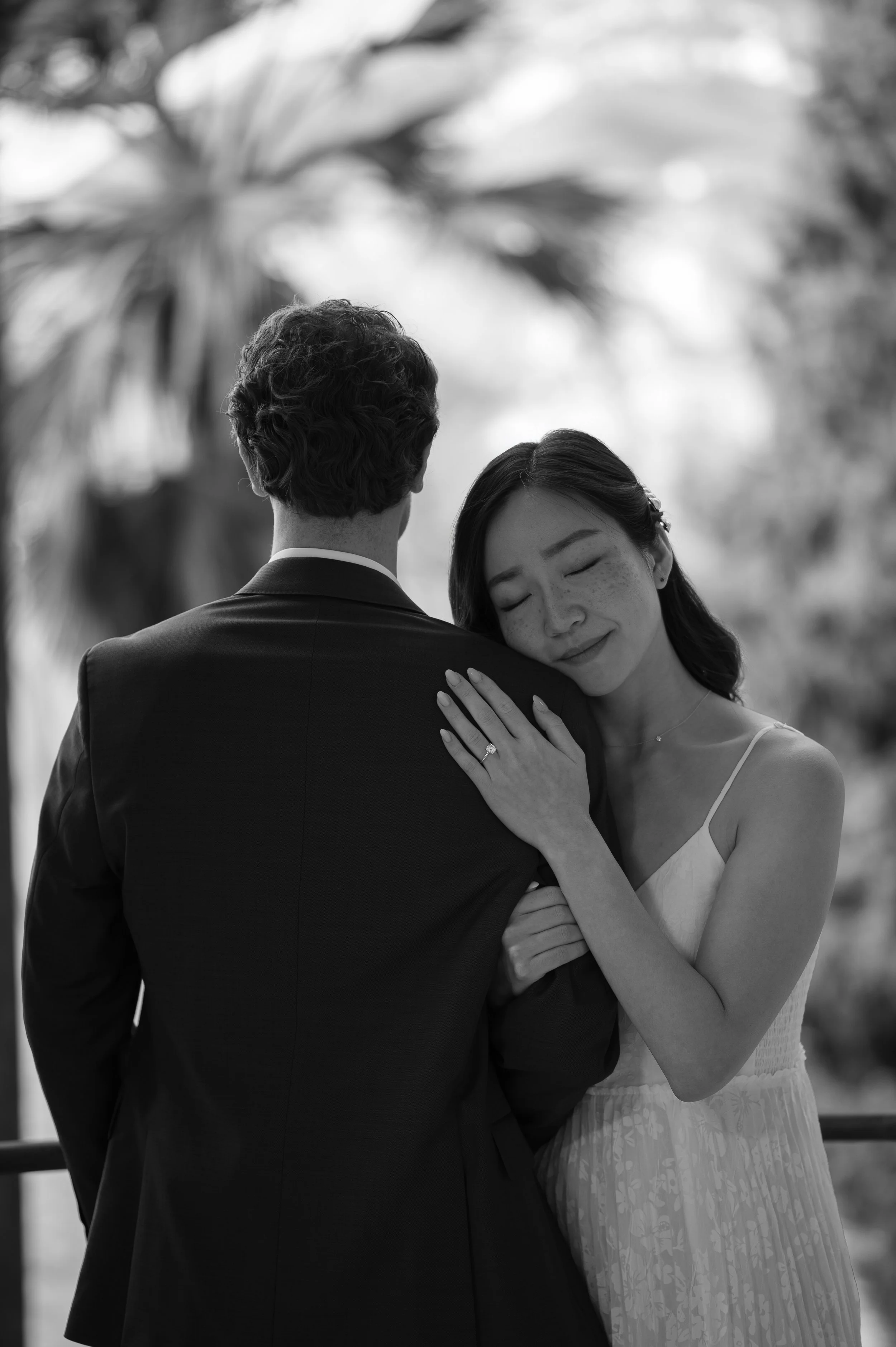 Bride resting her head on her partner's shoulder during an intimate wedding portrait captured in soft natural light.