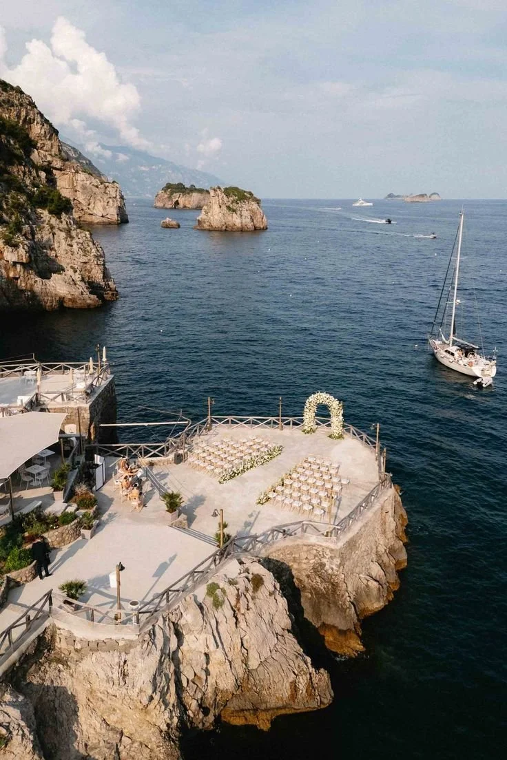 Cliffside wedding ceremony on the Amalfi Coast in Italy with ocean views and floral arch setup