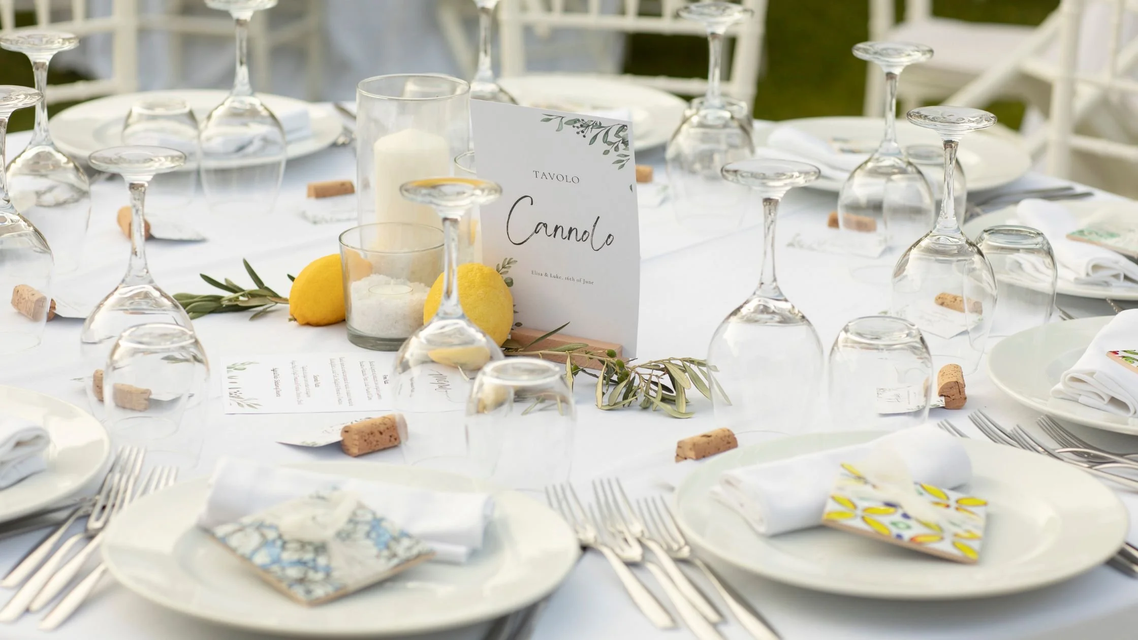 Elegant Italian wedding table setting in Sicily with white linens, lemons, olive branches, and personalised details for guests.