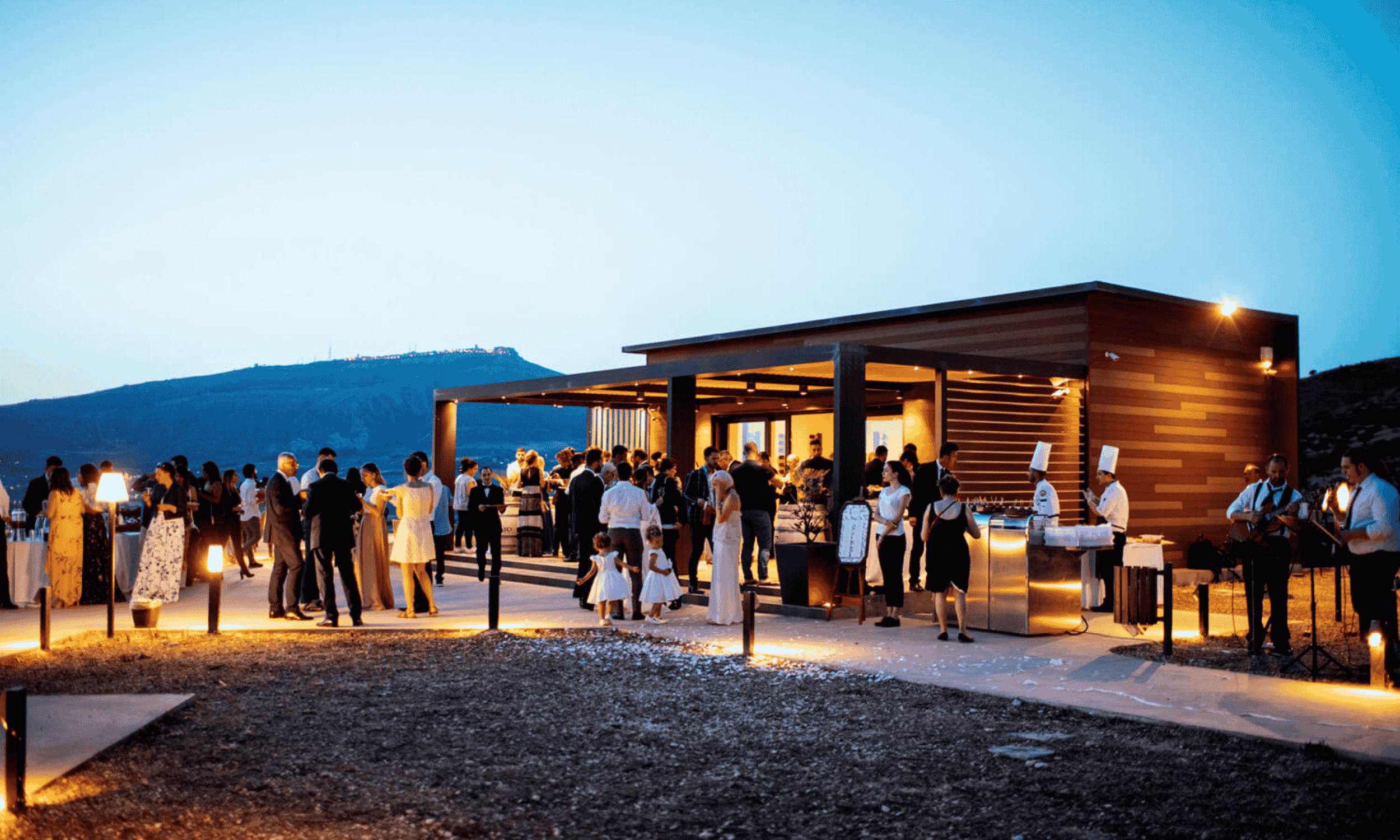 Guests mingling during an outdoor wedding cocktail hour in Italy at a modern venue with warm lighting at sunset