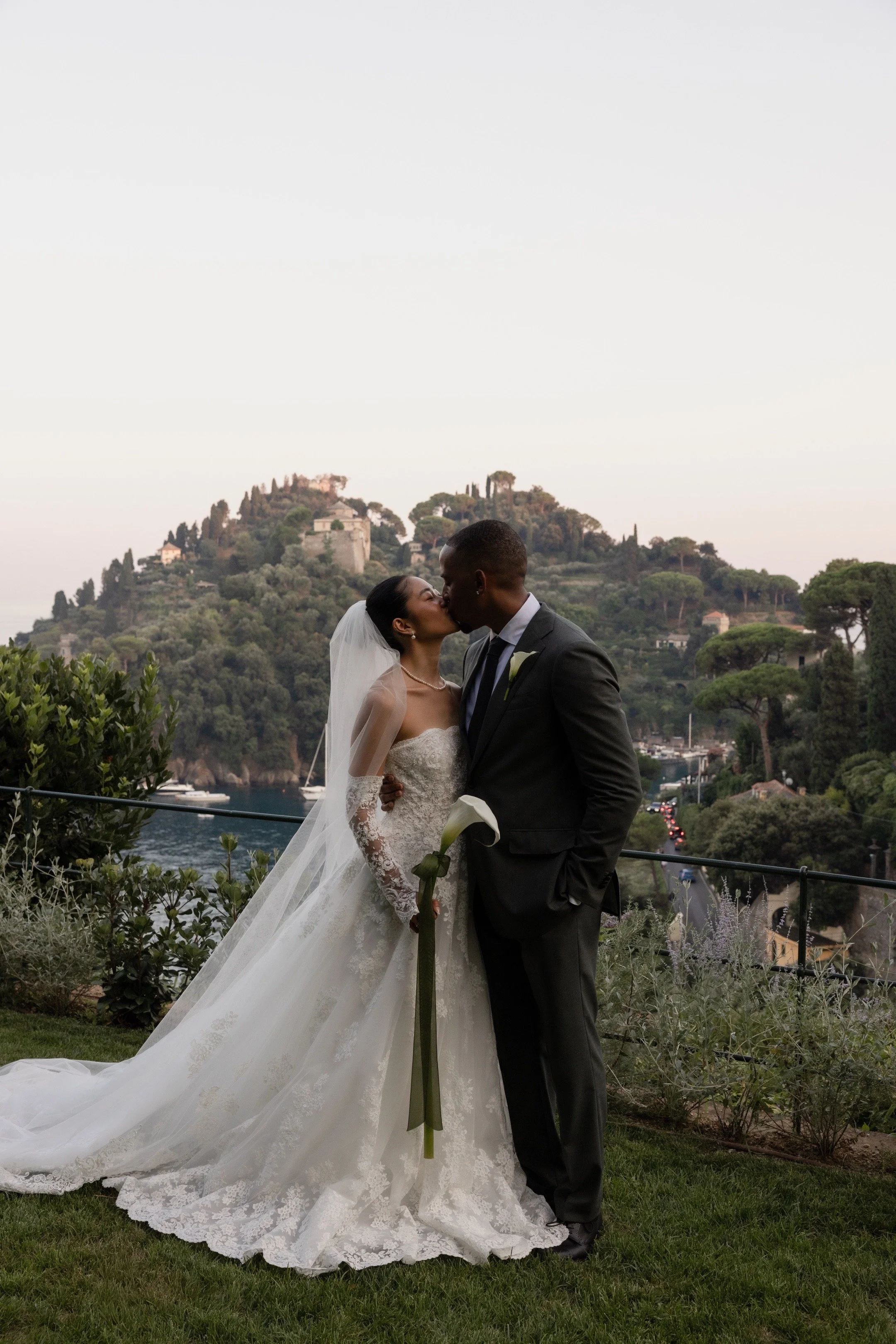 Bride and groom kissing in a garden overlooking the Italian coast, photographed by Lauren Young.