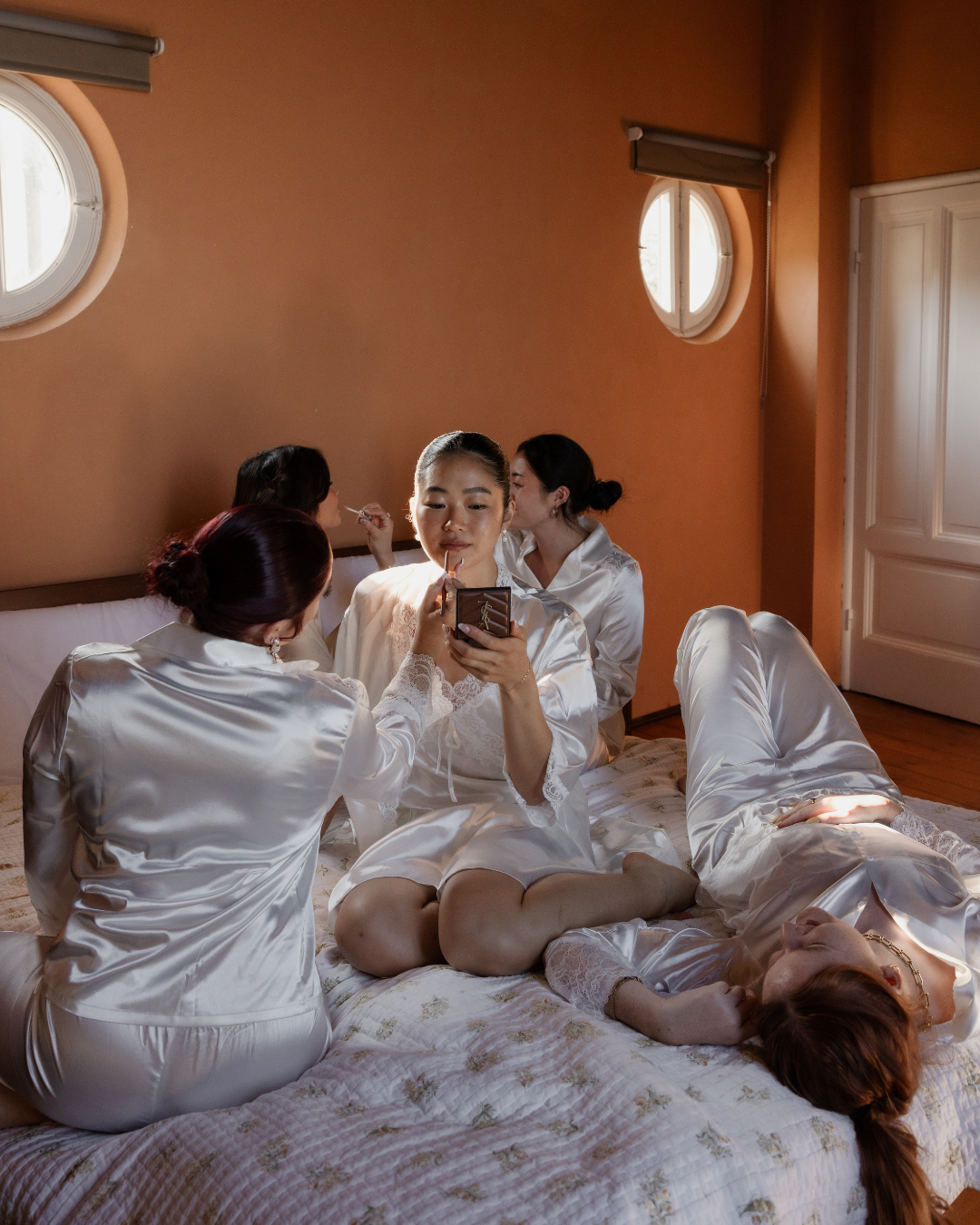 Bride and bridesmaids getting ready together in a warm Italian villa bedroom, photographed by Lauren Young.
