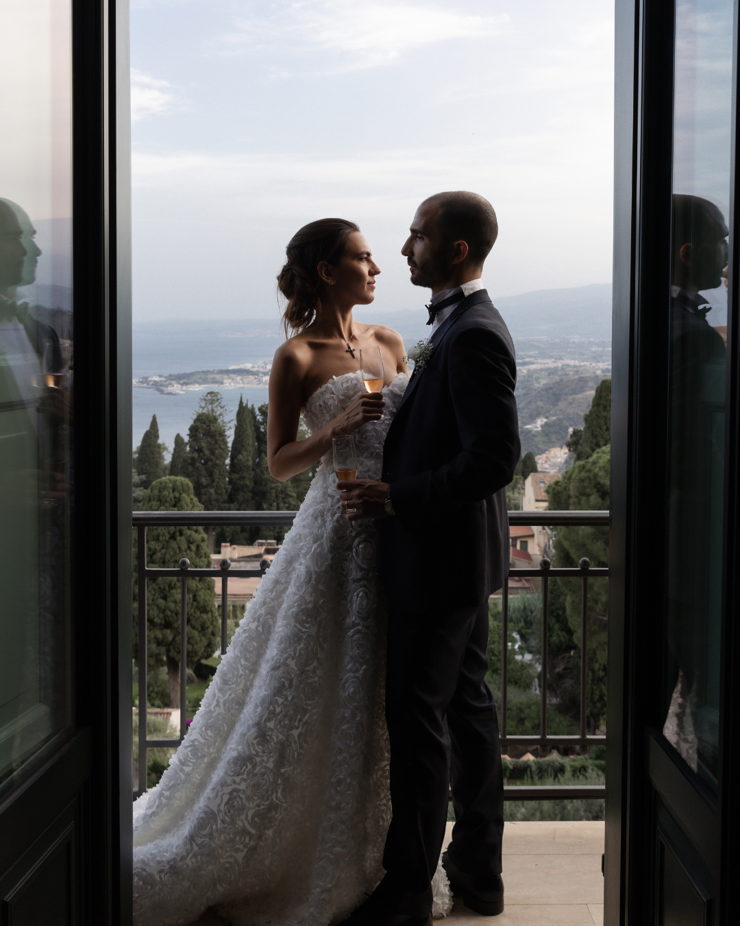 Bride and groom standing together on a balcony overlooking the Italian coastline, photographed by Lauren Young.