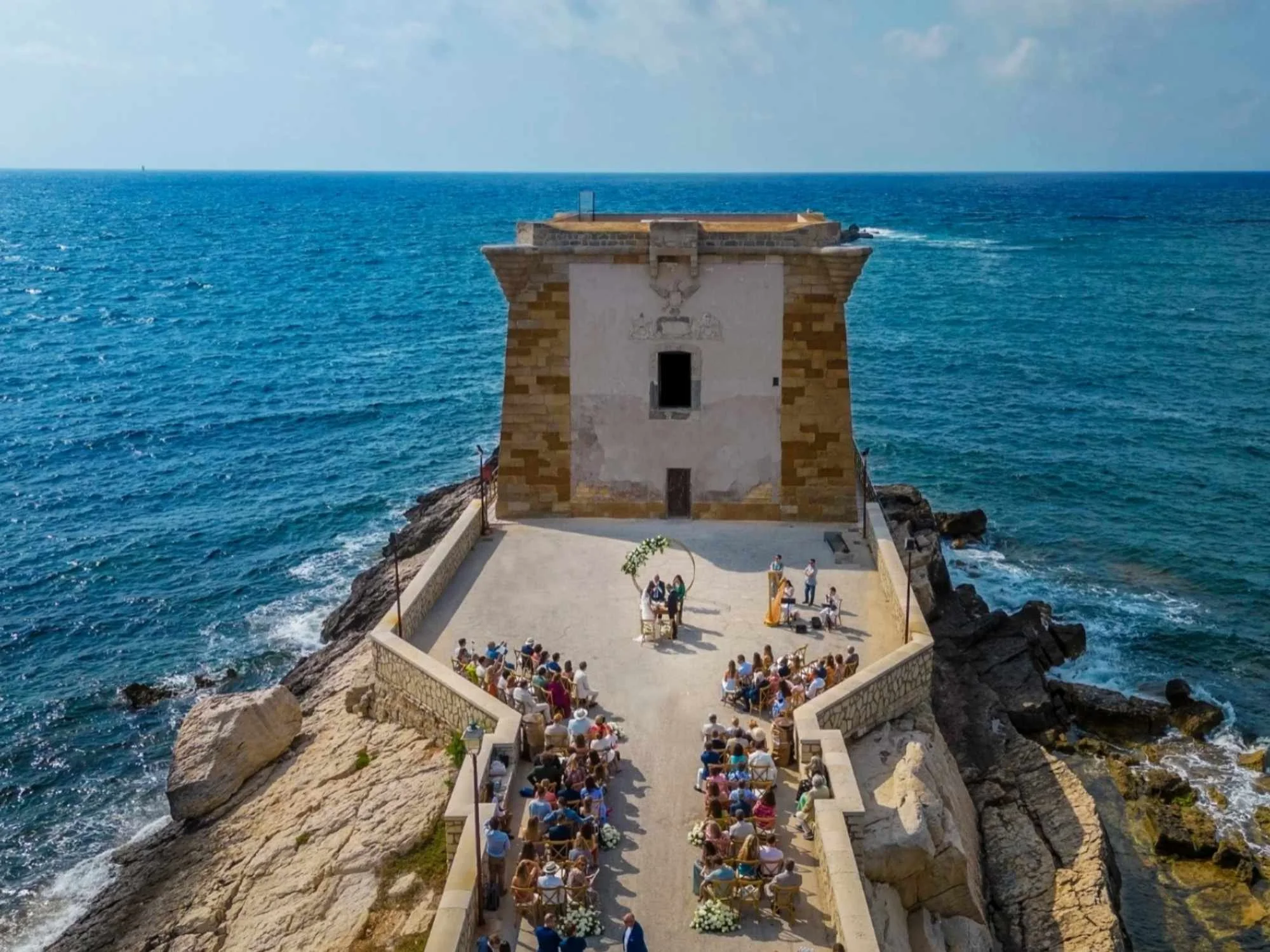 An unforgettable seaside ceremony at Torre di Ligny, with guests gathered on the edge of the Mediterranean.