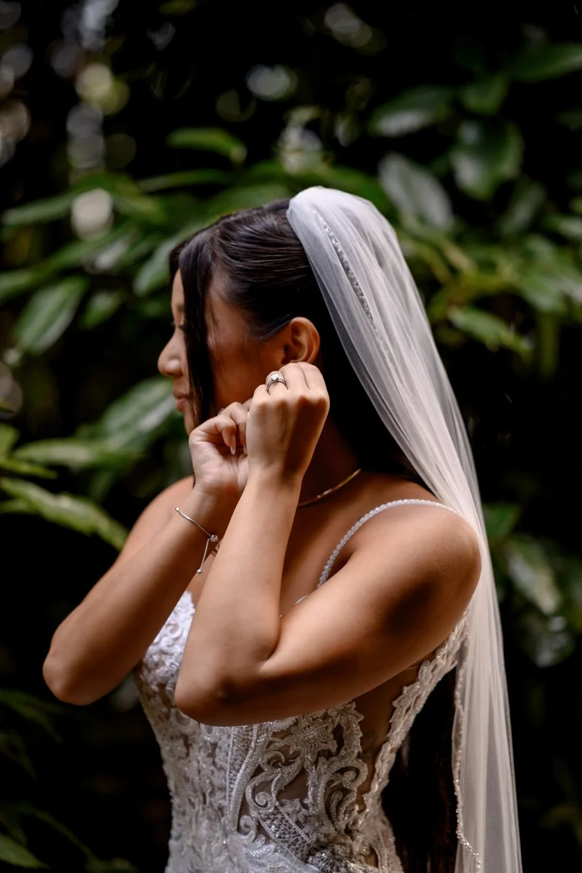 Bride putting on her earrings while getting ready for her wedding at Lake Como, Italy, wearing a lace wedding dress and long veil.