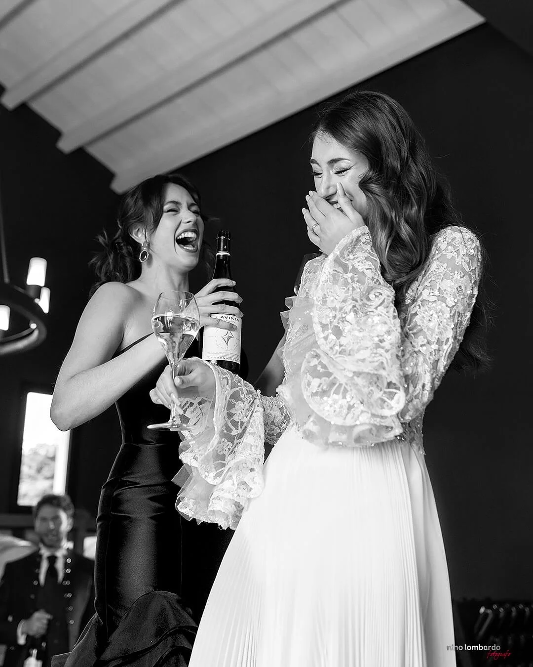 Black and white photo of bride laughing while getting ready with champagne before the wedding