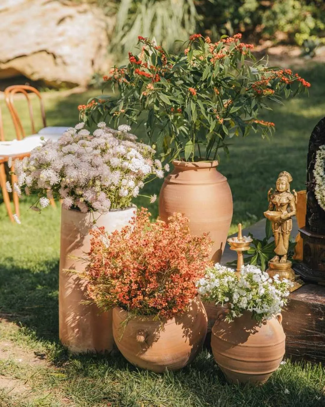 Terracotta pots with wild, meadow-style florals at an Italian garden wedding ceremony.