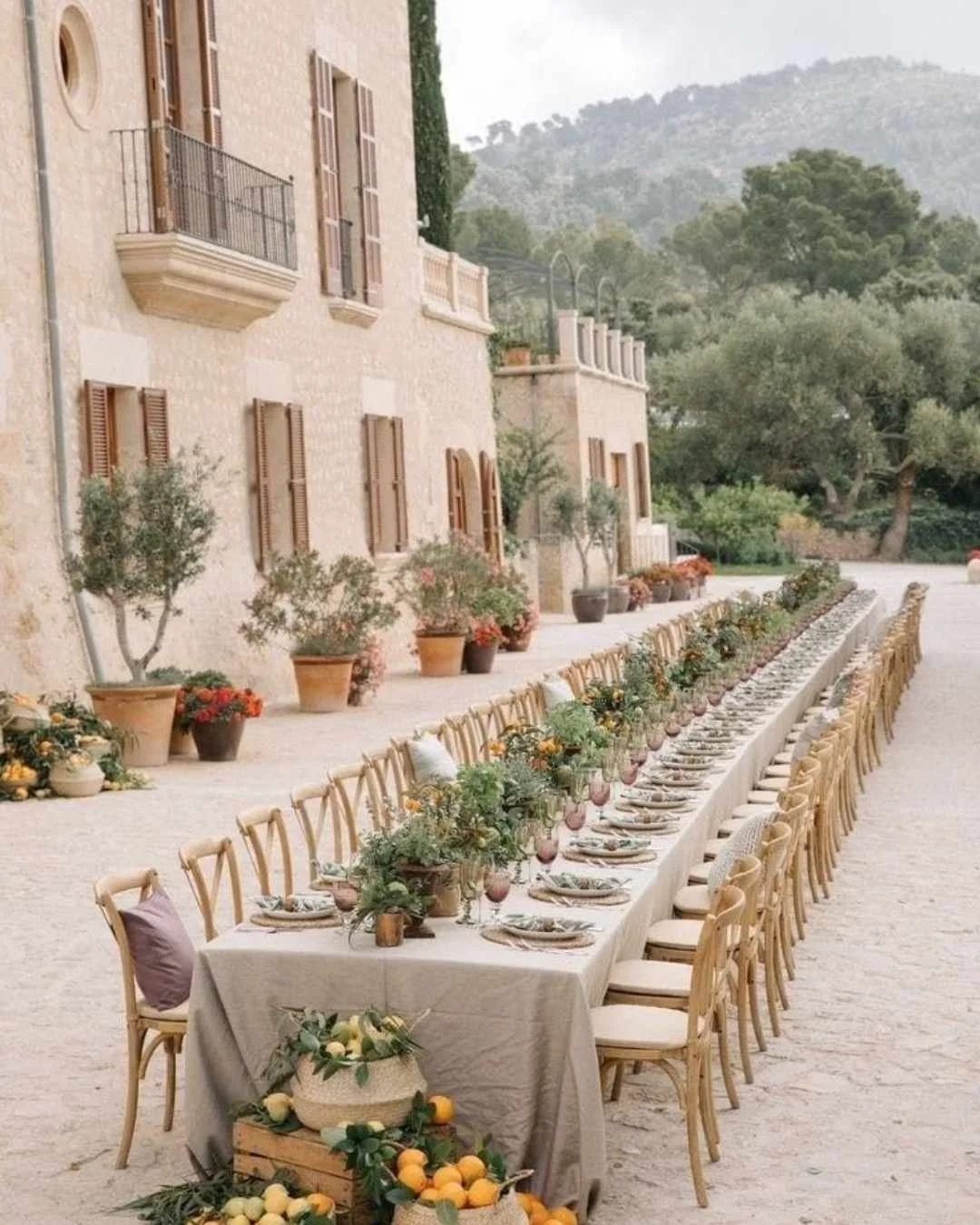 Long villa courtyard dining table styled with lemons, herbs and terracotta accents for a Mediterranean Italian wedding.