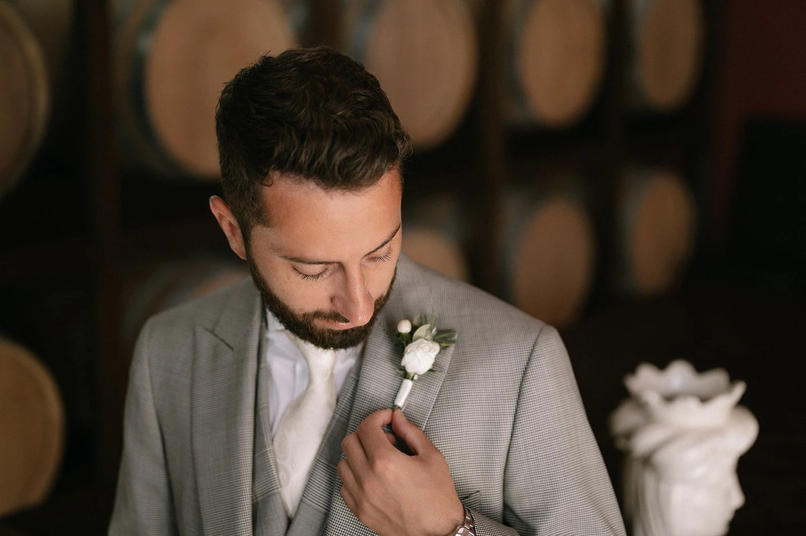 Groom adjusting a white floral boutonniere while getting ready for an Italian destination wedding.