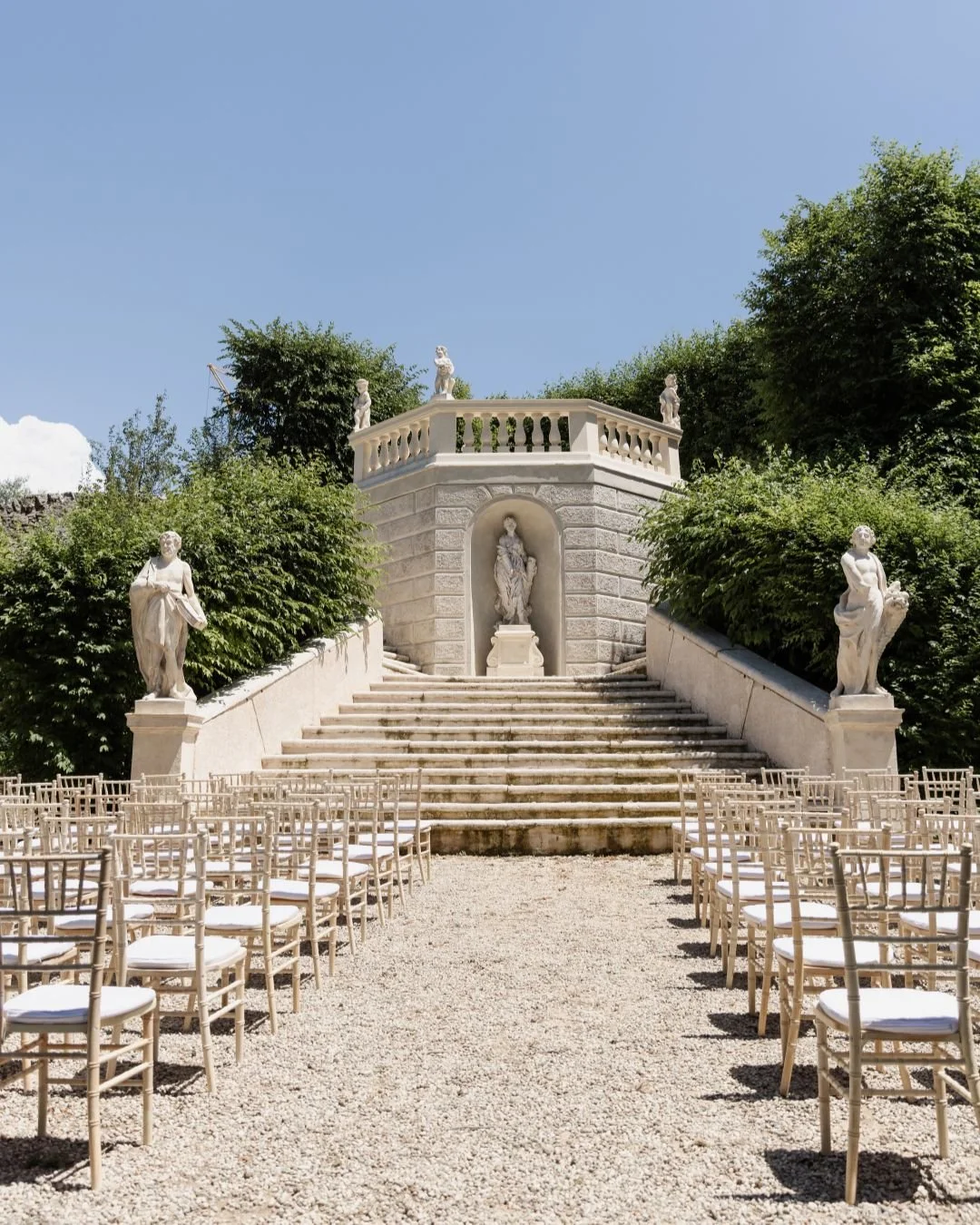 Outdoor wedding ceremony set in an Italian villa garden with rows of chairs facing a grand stone staircase.