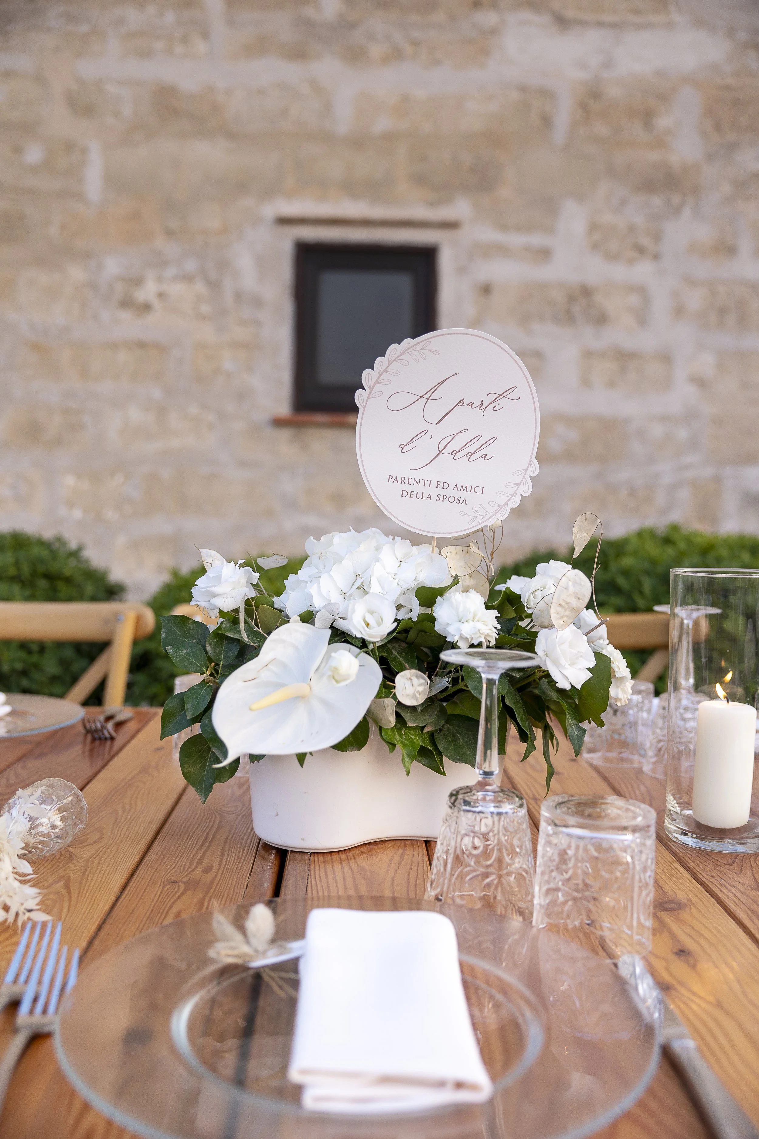 Elegant white wedding table centrepiece in Sicily with anthurium, candles, and refined floral styling by Alla Flora Giapponese.