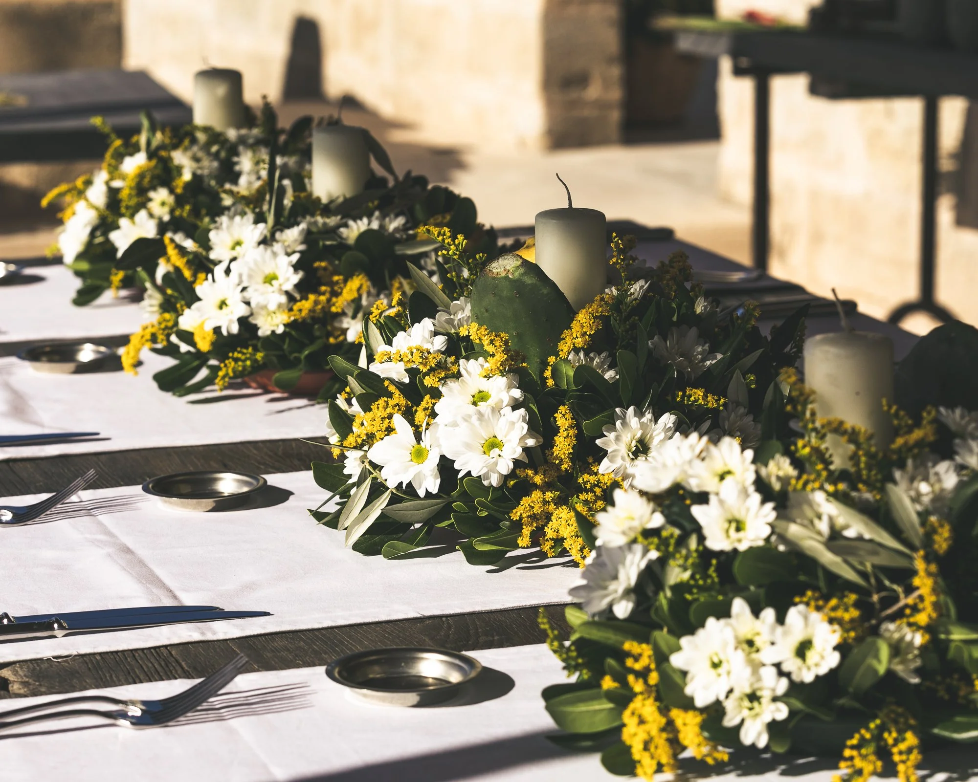 Outdoor Sicily wedding table styling with yellow and white flowers, greenery, candles, and Mediterranean floral design by Alla Flora Giapponese.