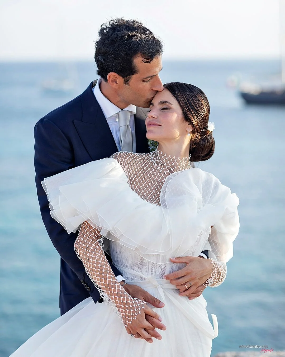 Bride and groom embracing by the sea in Sicily with soft light and elegant wedding styling