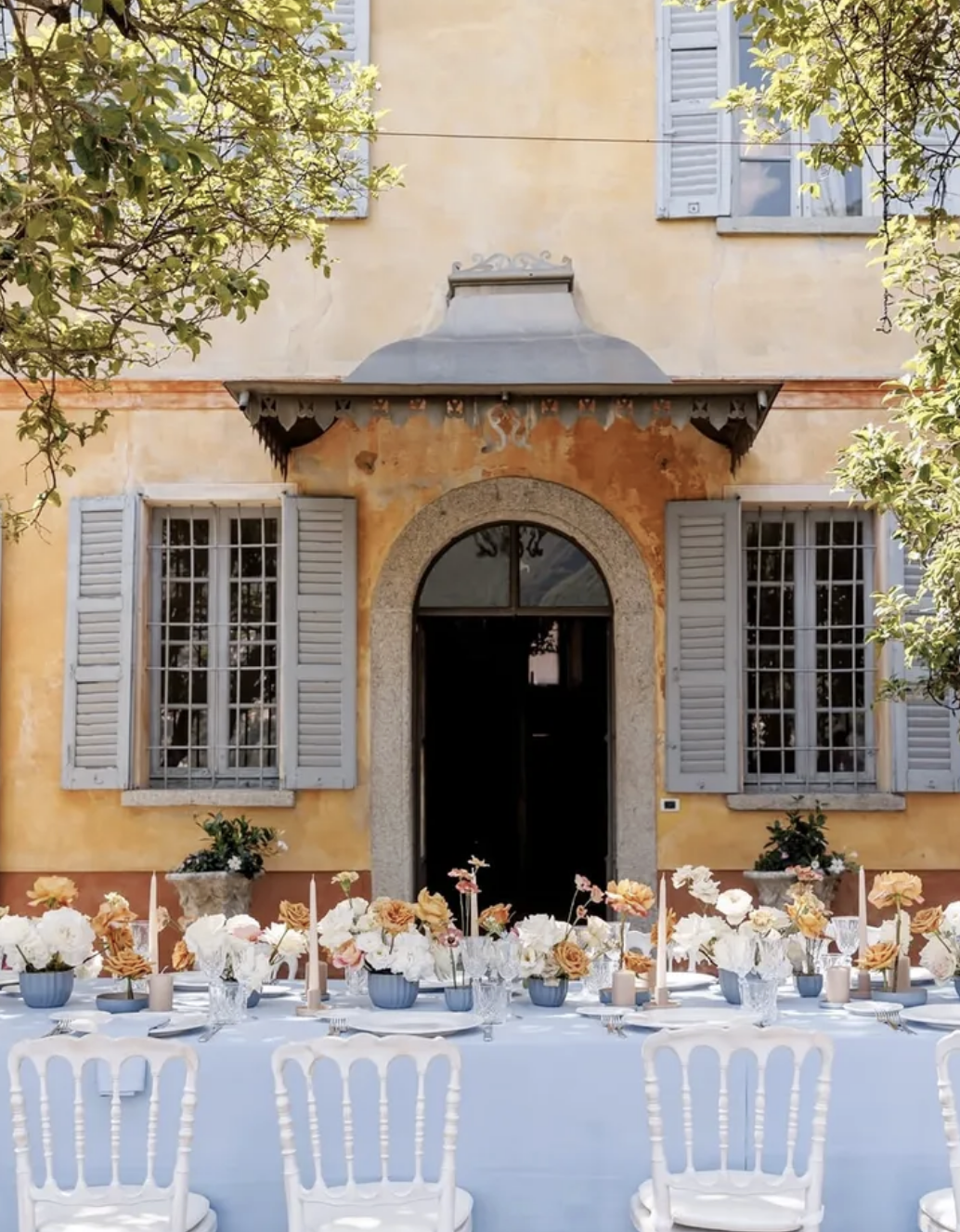 Elegant outdoor wedding reception table styled with flowers and candles in front of a historic Italian villa.