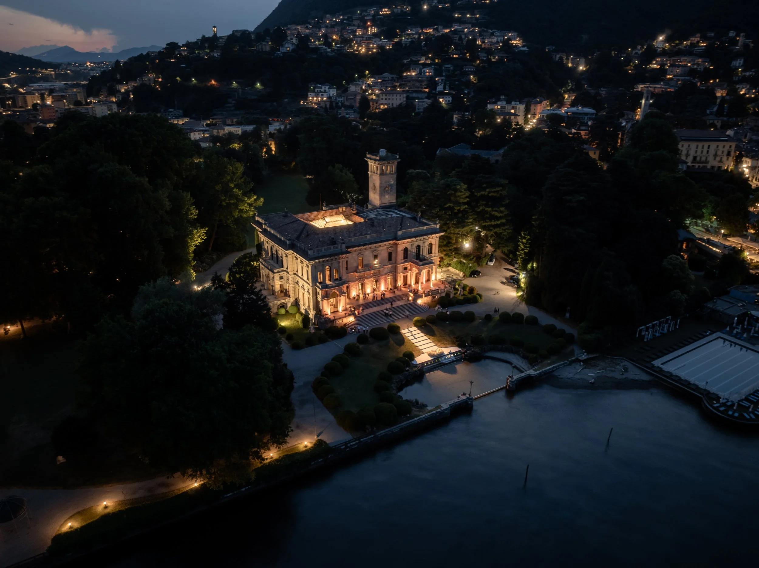 Aerial view of an elegant Lake Como villa illuminated at dusk during a wedding celebration.