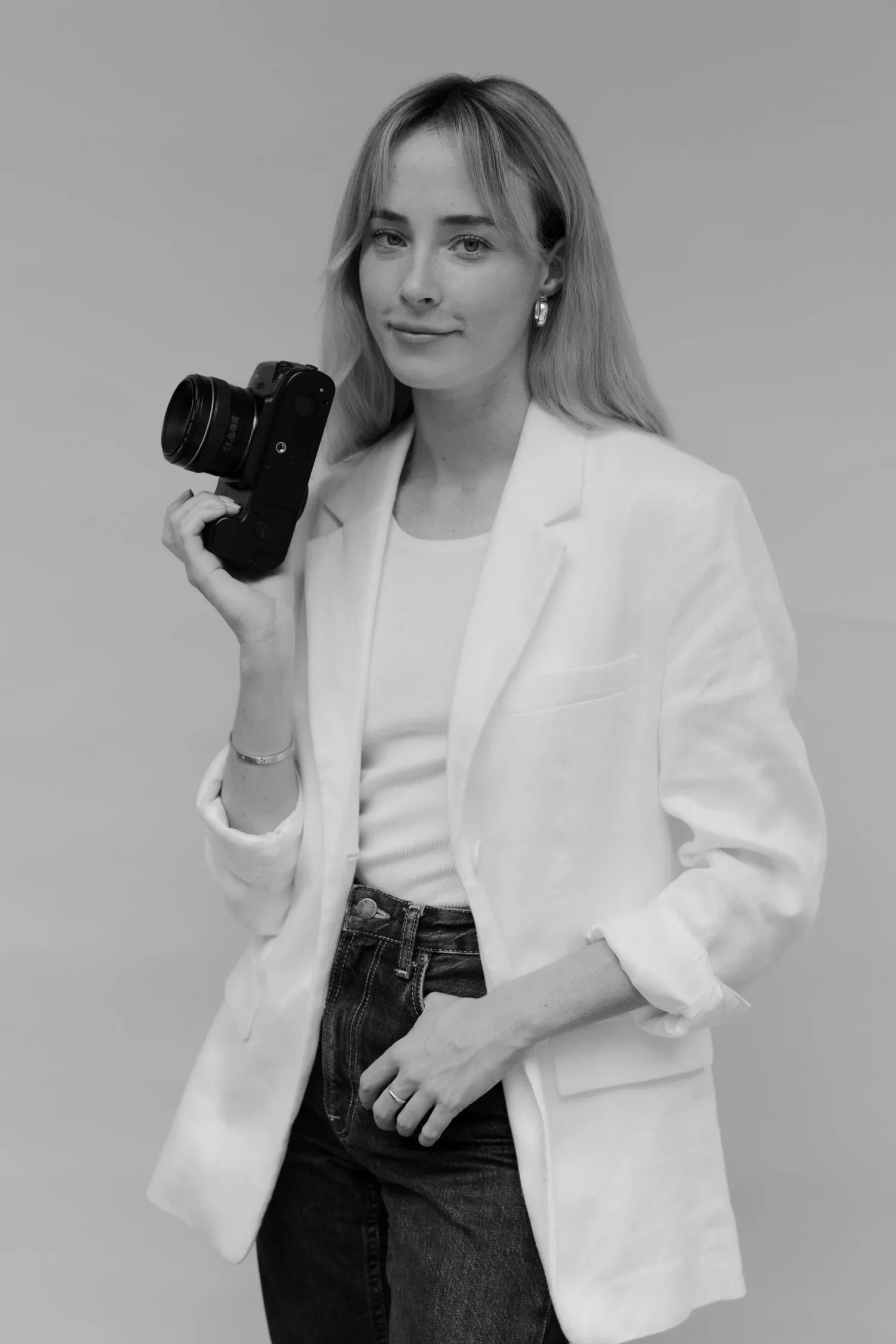 Black and white portrait of wedding photographer Lauren Young holding a camera.