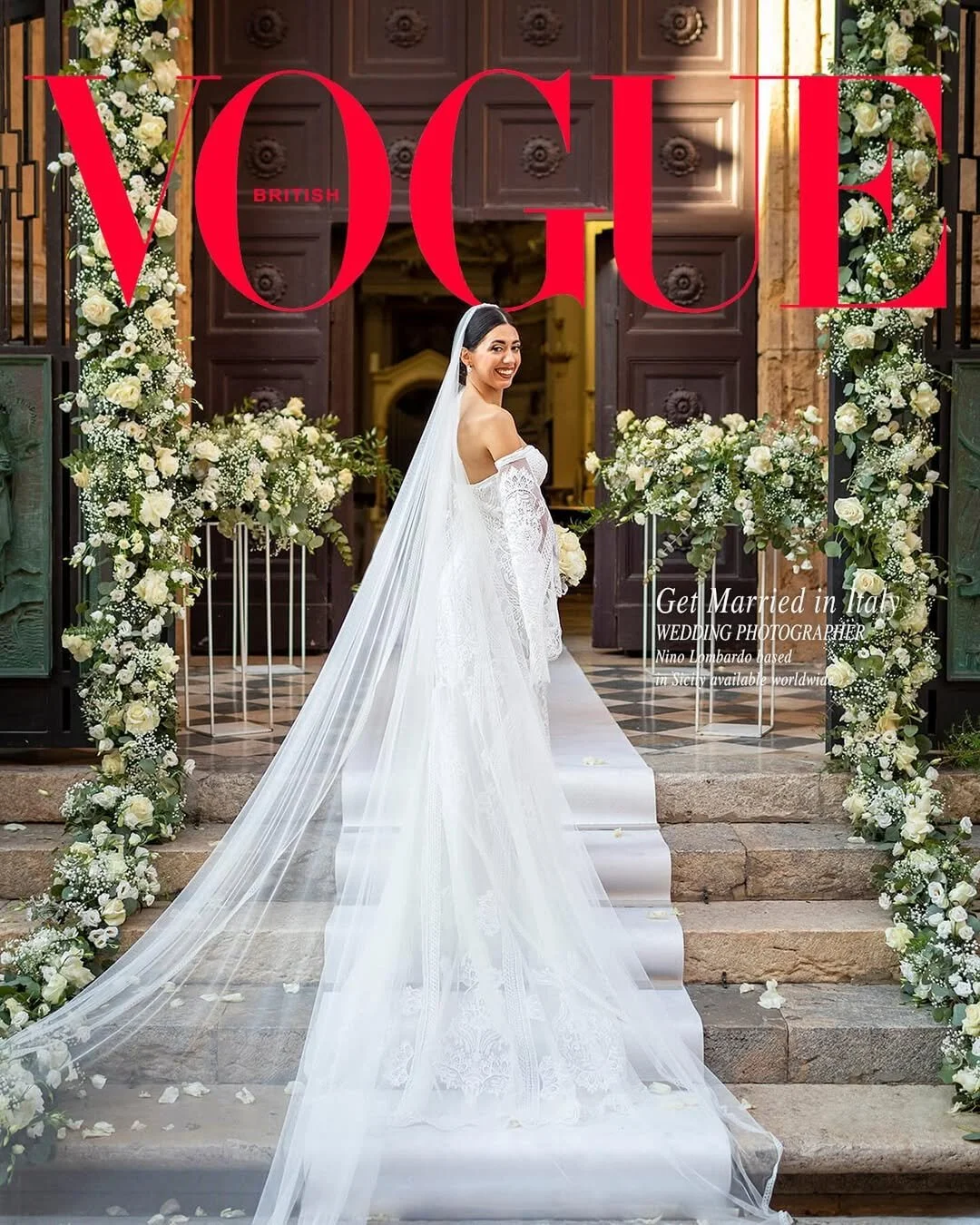 Bride in a lace wedding dress with long veil standing at a church entrance in Italy, surrounded by white floral arrangements and elegant doorway decor
