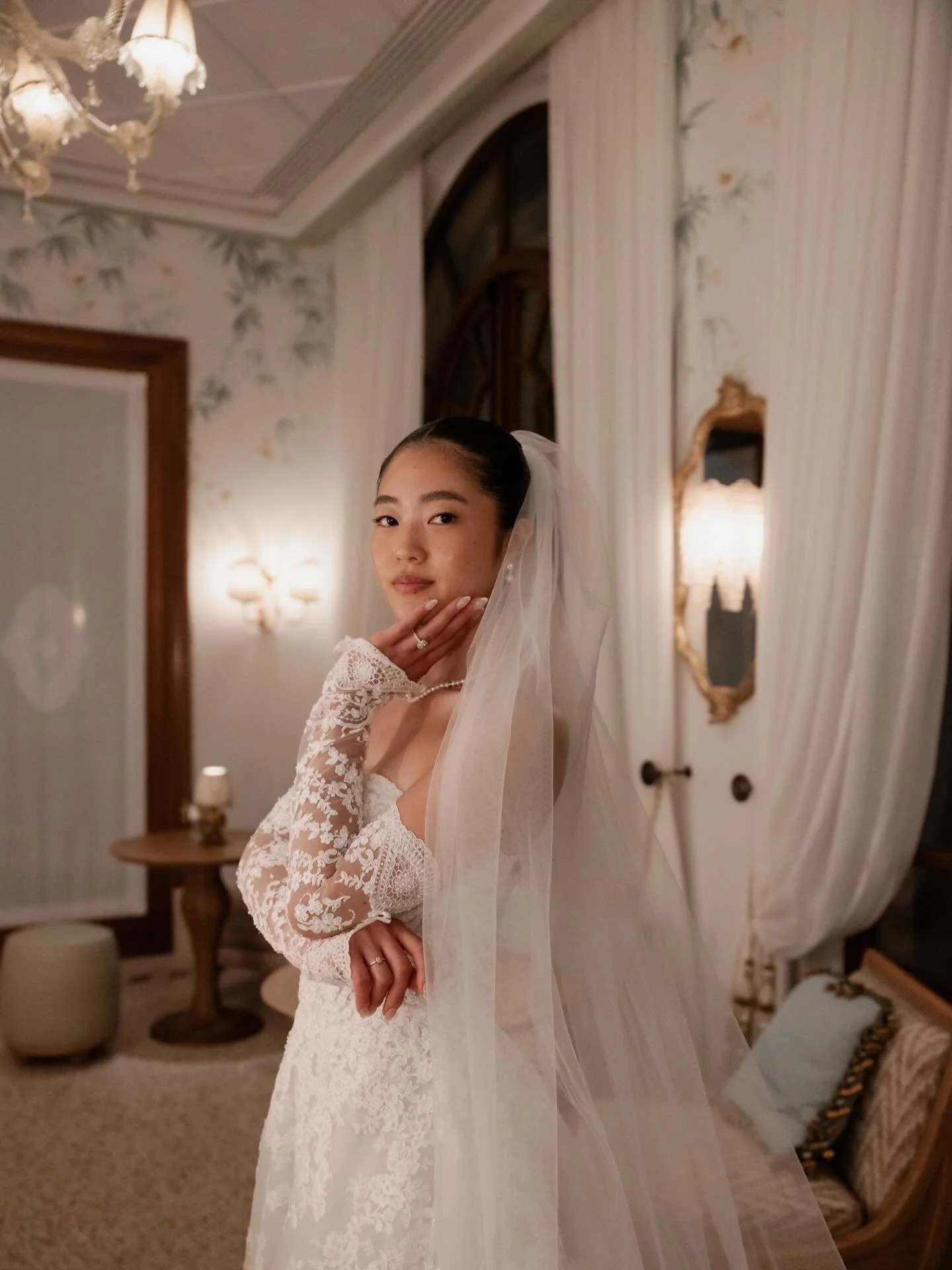 Bride in a lace wedding dress and long veil posing inside an elegant Italian venue, photographed by Lauren Young.