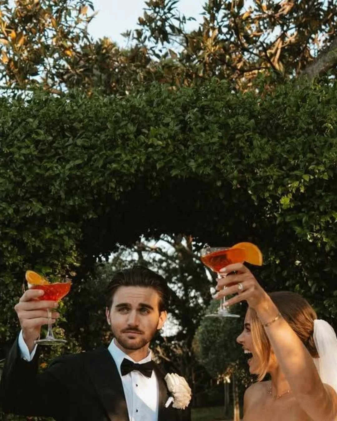 Bride and groom raising Negronis during cocktail hour, celebrating with classic Italian spritz-style cocktails.