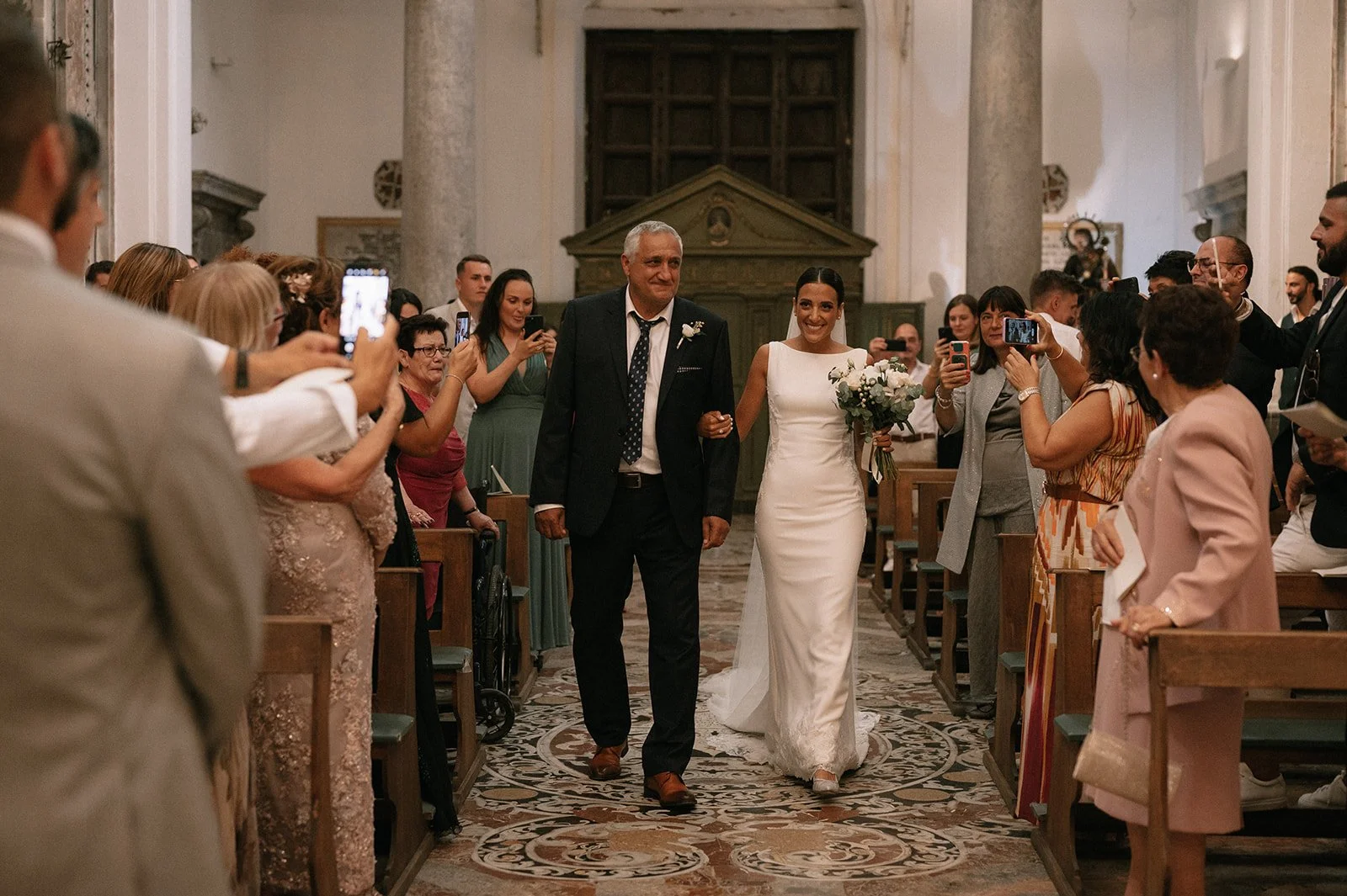 Bride walking down the aisle during a Sicilian church wedding holding an elegant bouquet by Alla Flora Giapponese.