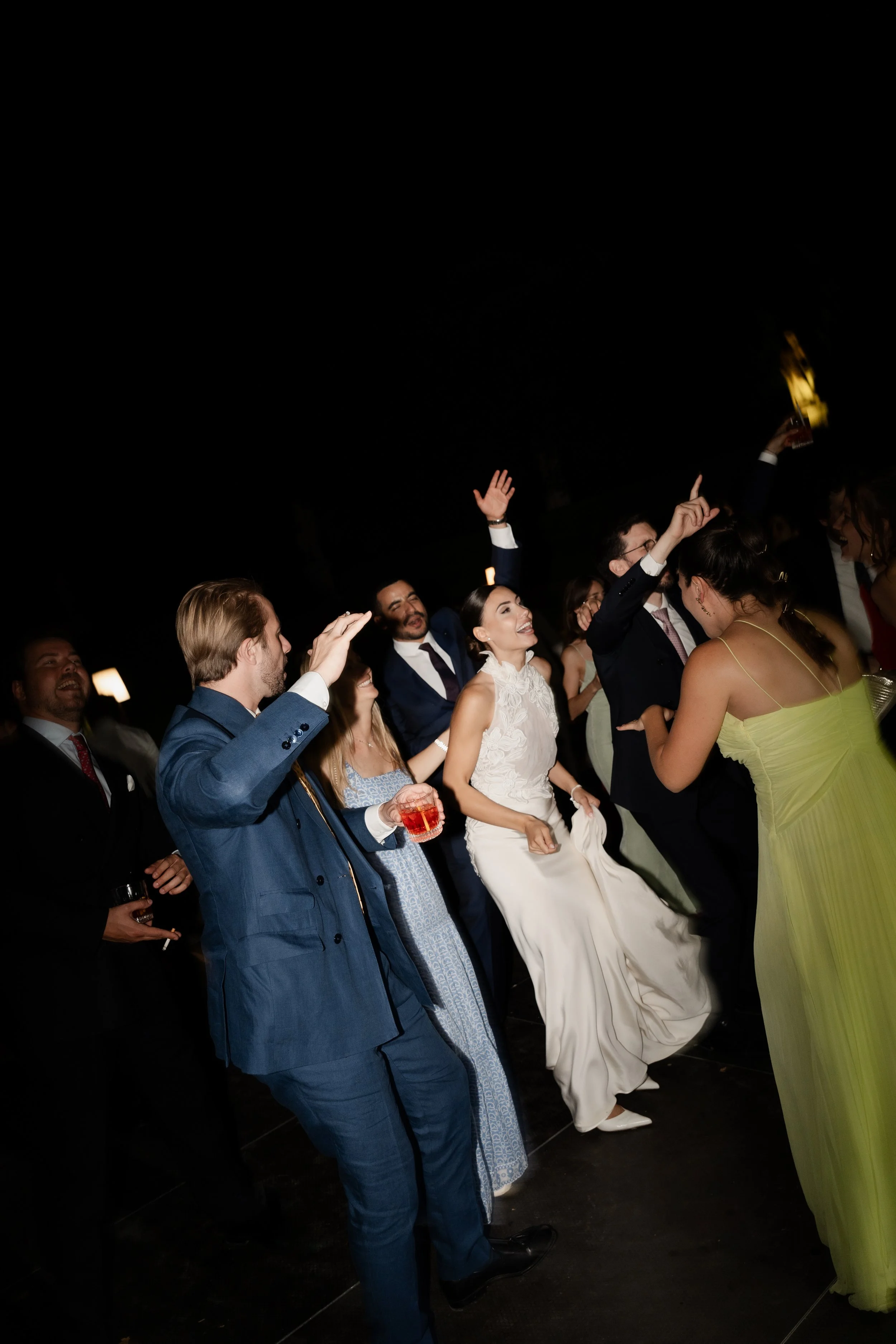 Bride dancing with wedding guests during a lively evening reception in Italy, photographed by Lauren Young.