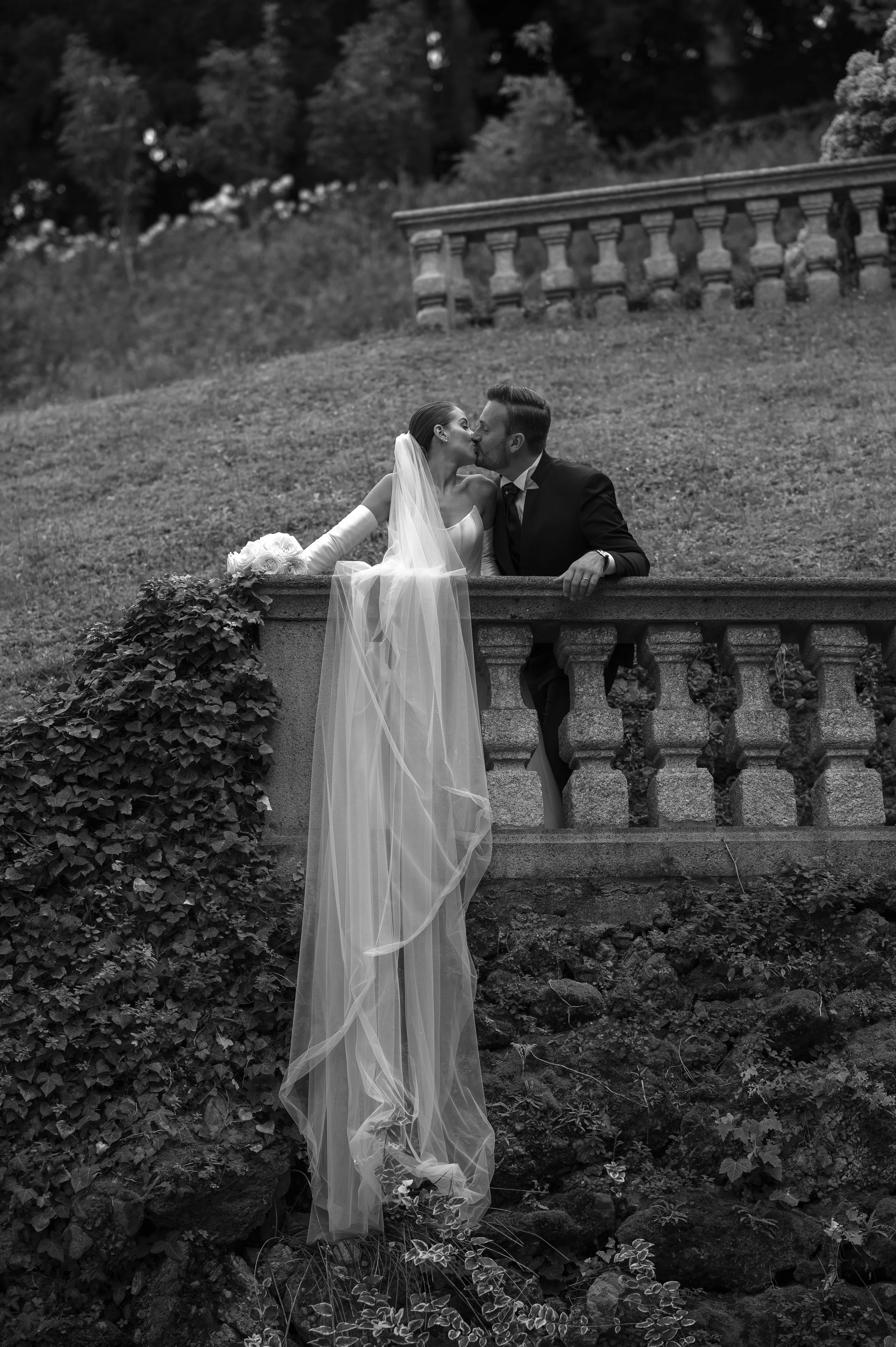 Bride and groom sharing a quiet kiss on a stone terrace during an elegant wedding portrait session in Italy.