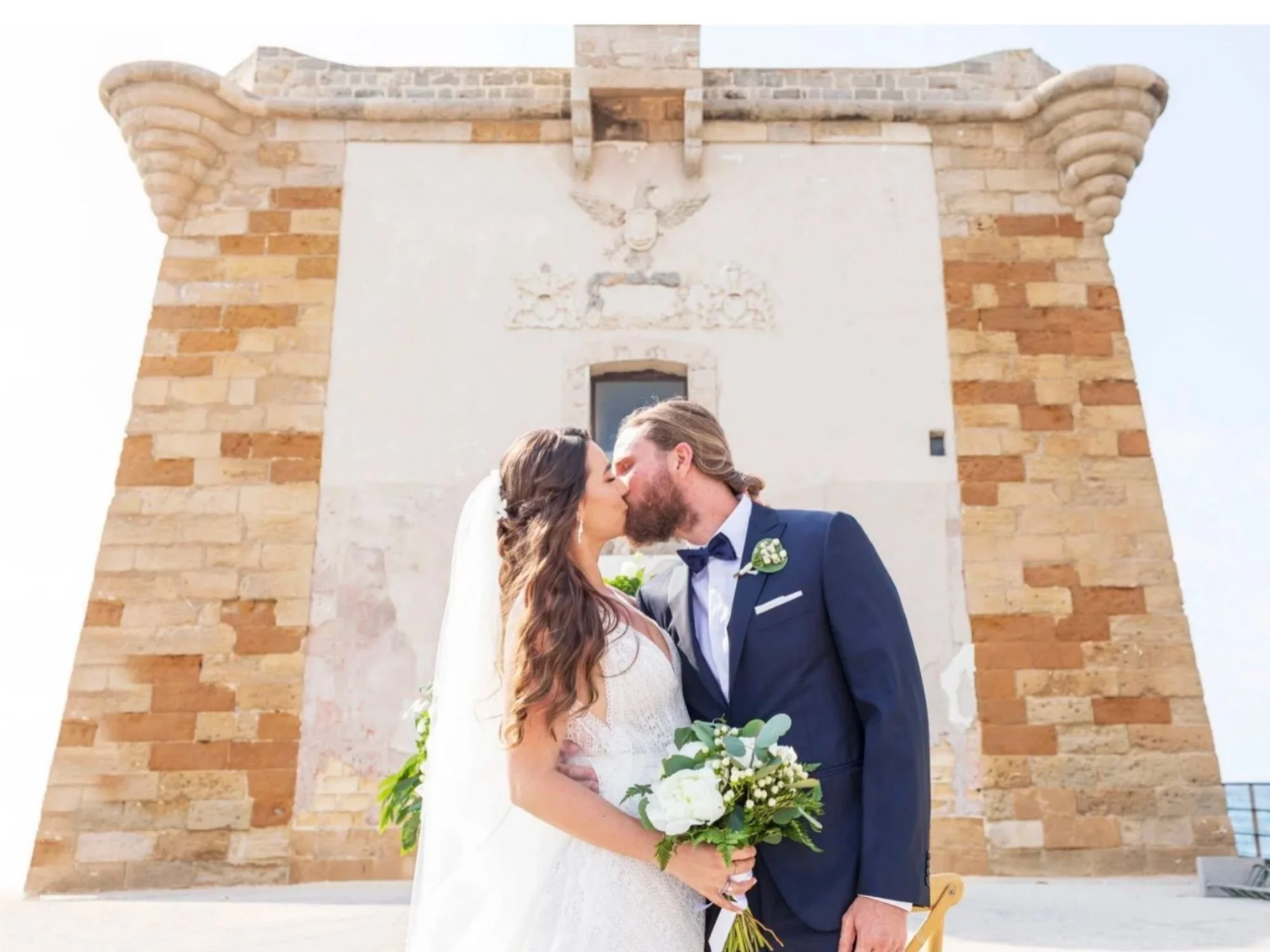 A romantic kiss in front of Torre di Ligny in Trapani, Sicily — the perfect symbol of love by the sea.