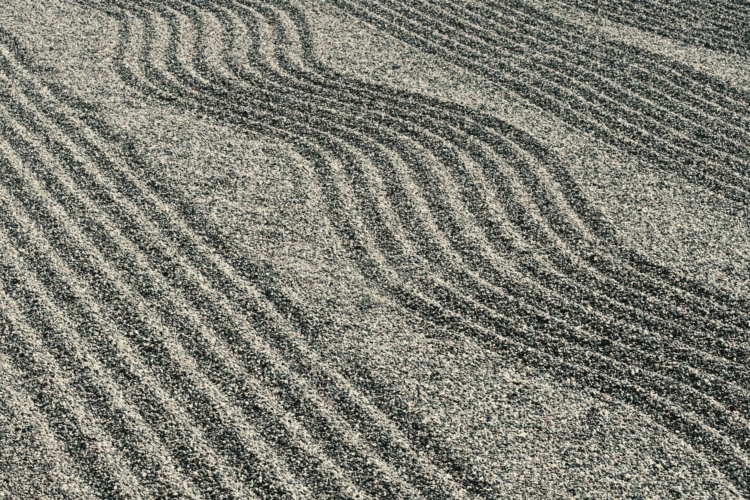 Close-up of a gravel surface with evenly spaced, parallel lines and small pebbles.
