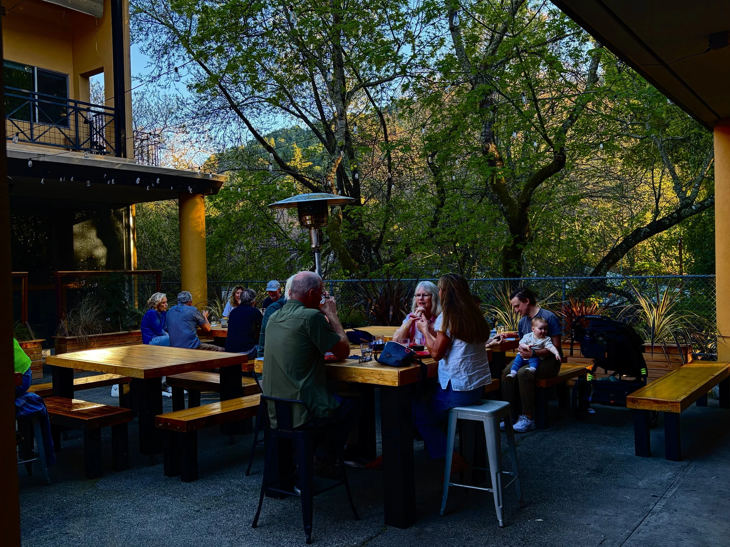 People sitting at outdoor tables on a restaurant patio. Dog friendly. Serves pizza, salads, and sandwiches.