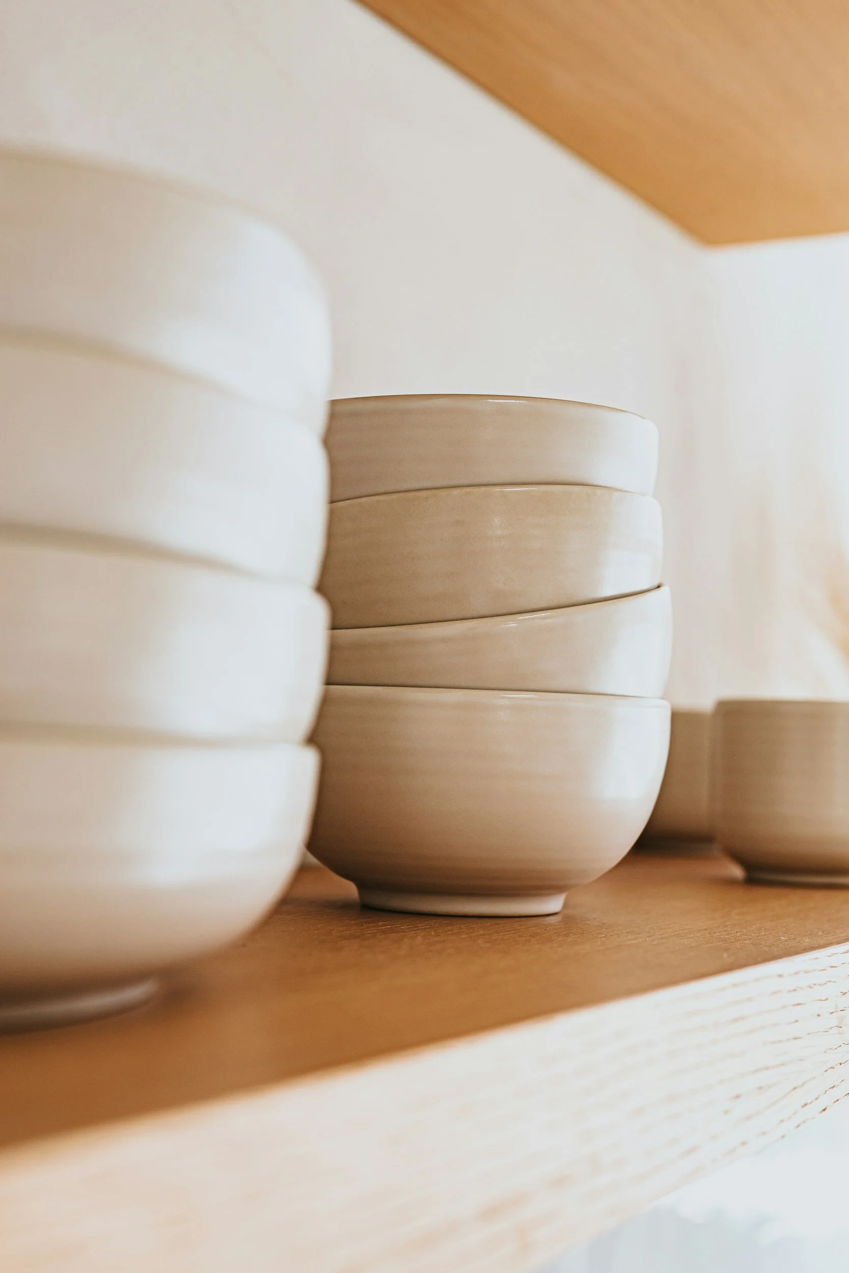 Stacked ceramic bowls on a wooden shelf