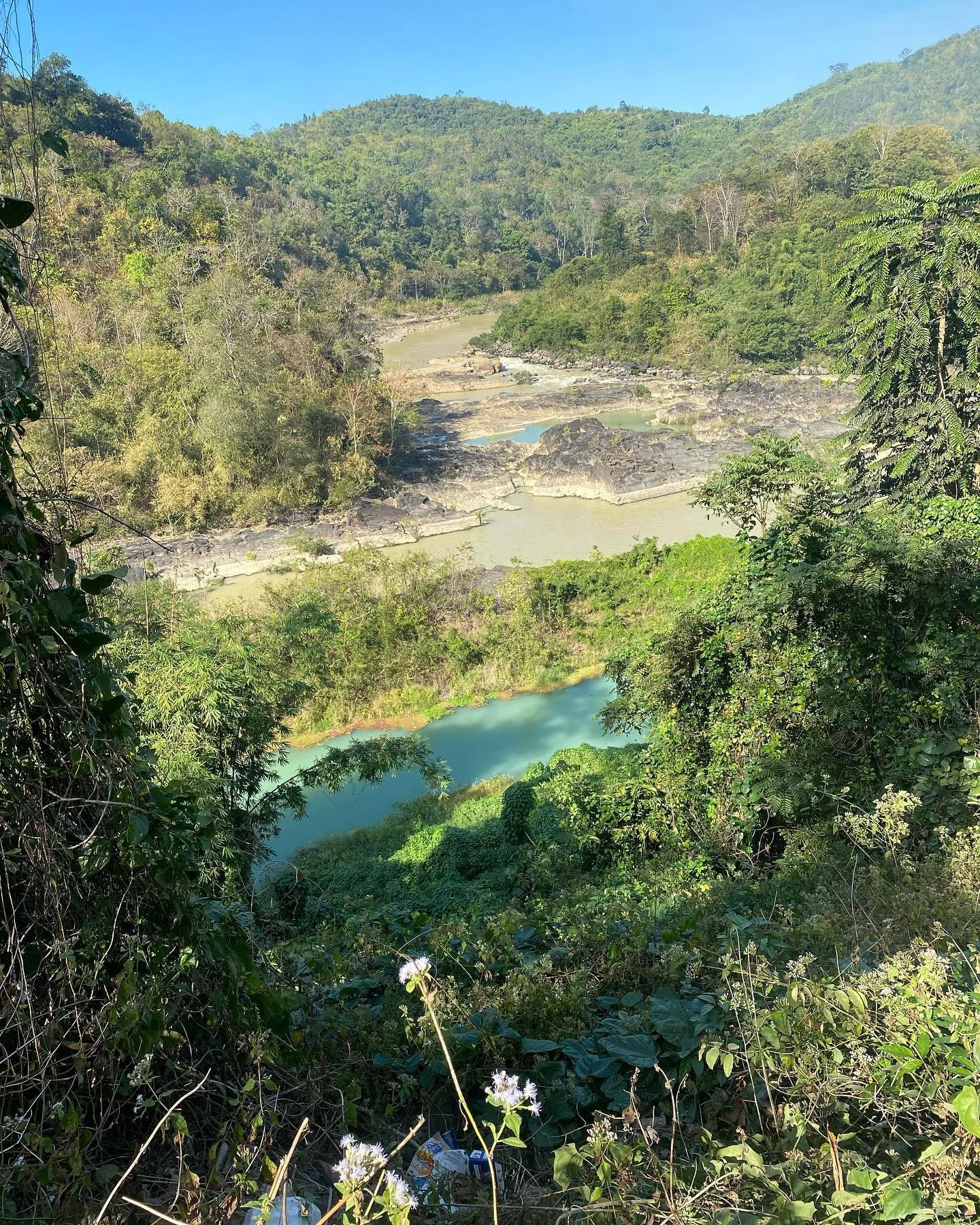 Scenic landscape with a winding river, lush greenery, and hills in the background.